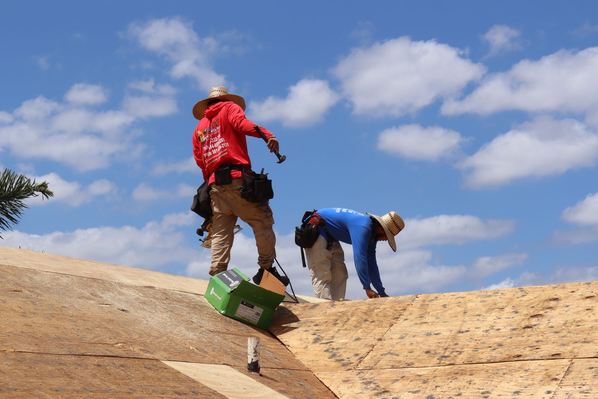 A person stands on a ladder cleaning a chimney on a tiled roof.