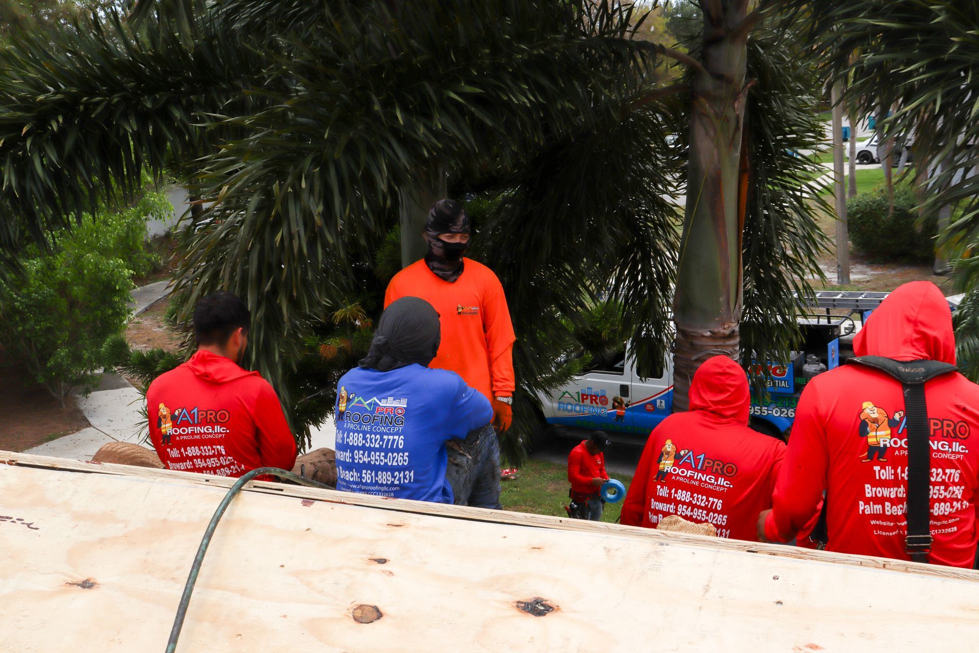 A roofer wearing work gloves installs terracotta-colored roof tiles onto a wooden frame on a sloped roof.