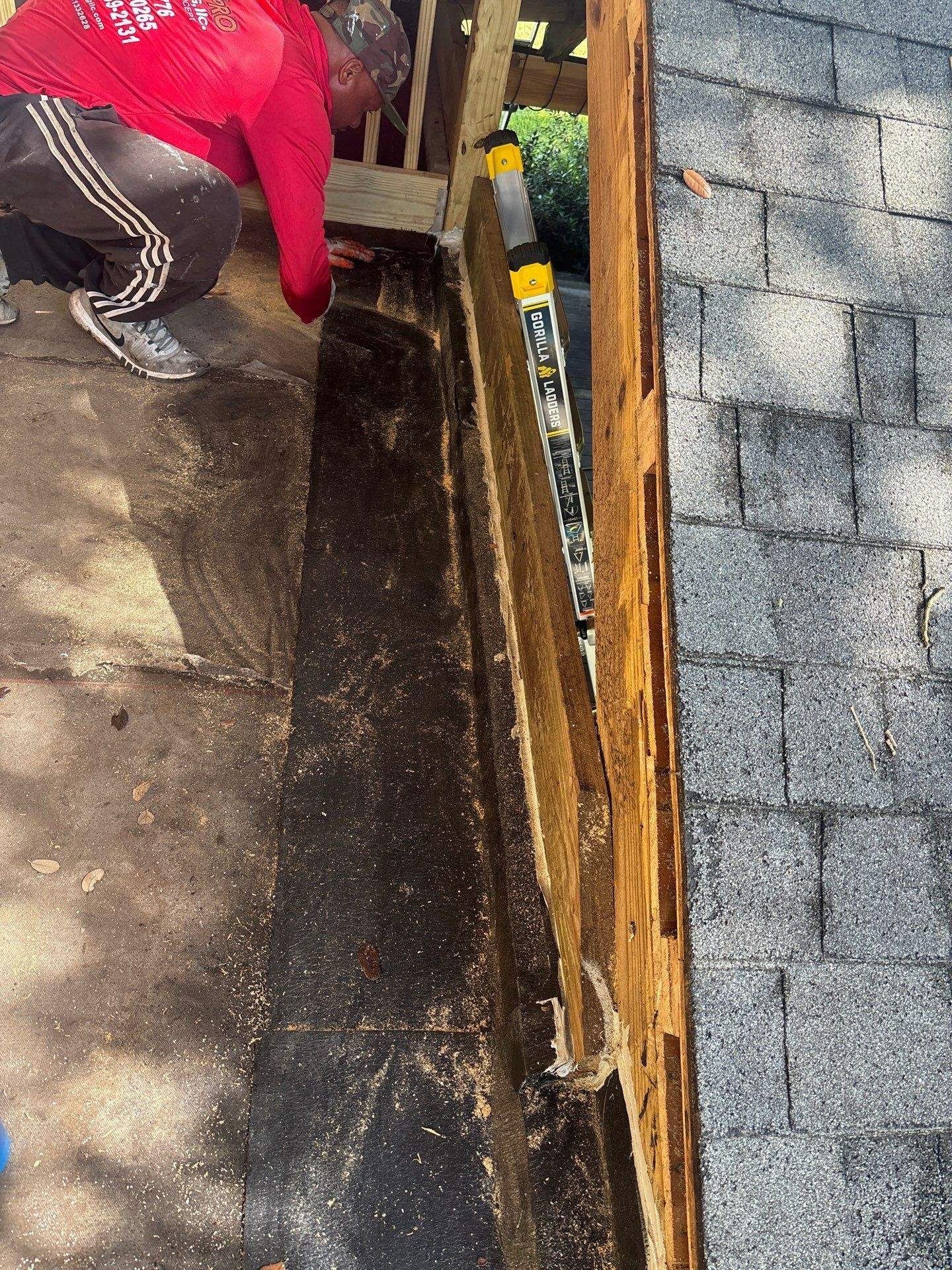 A high-angle view looking down at a gray shingled roof with a pool and houses visible in the surrounding neighborhood.