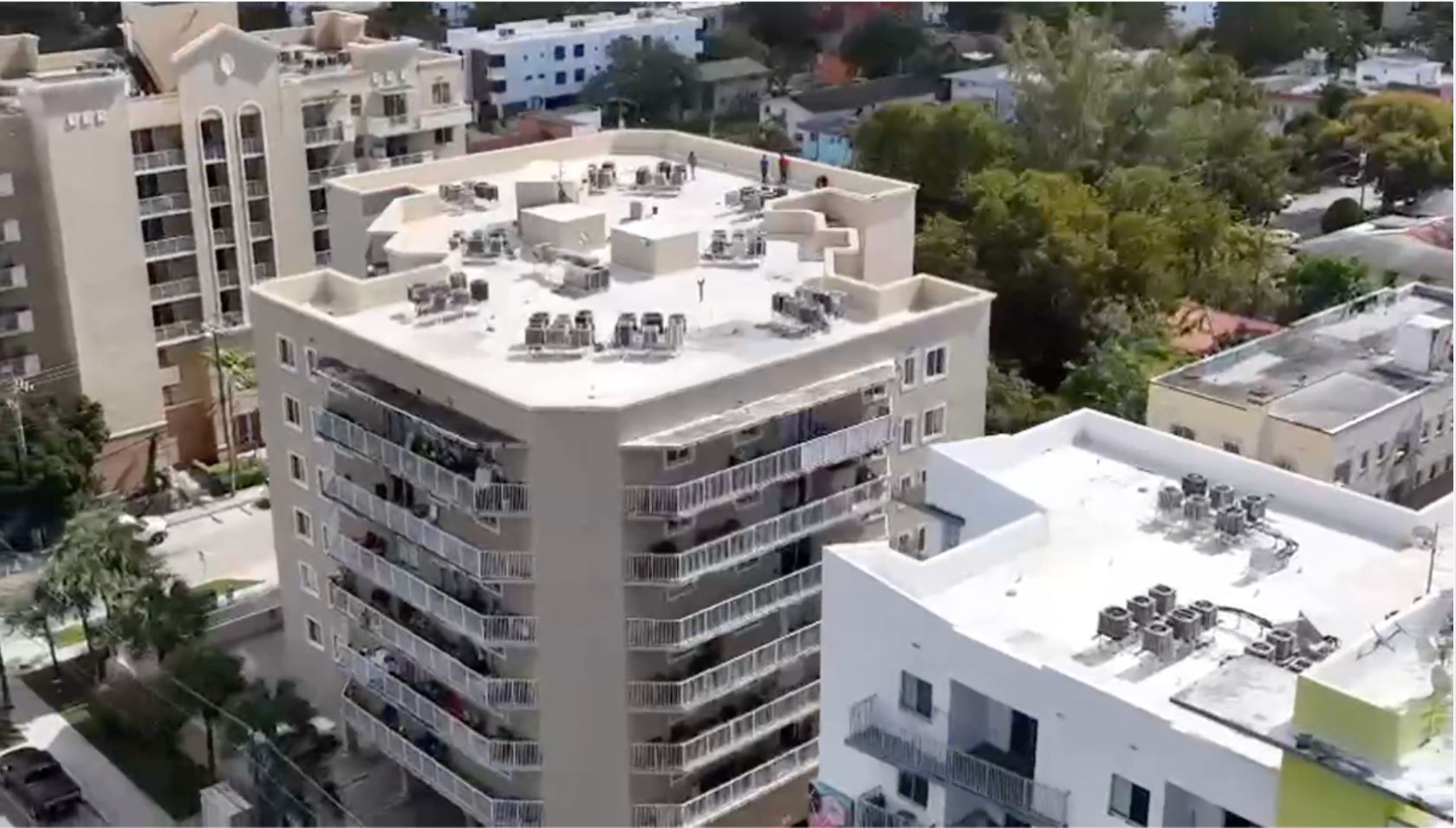 A row of modern two-story suburban houses with neutral siding and peaked roofs along a paved street under a blue sky.