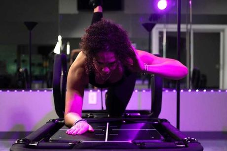 A woman is doing push ups on a machine in a gym.