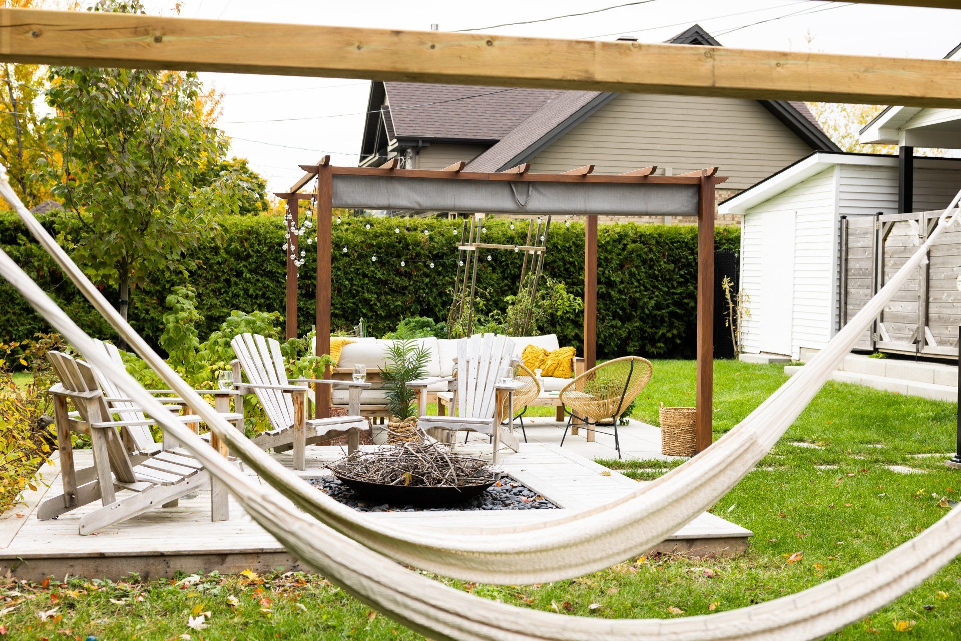 Deux chaises longues et une petite table sous un grand parasol beige déporté sur une terrasse ensoleillée au bord d'une piscine.