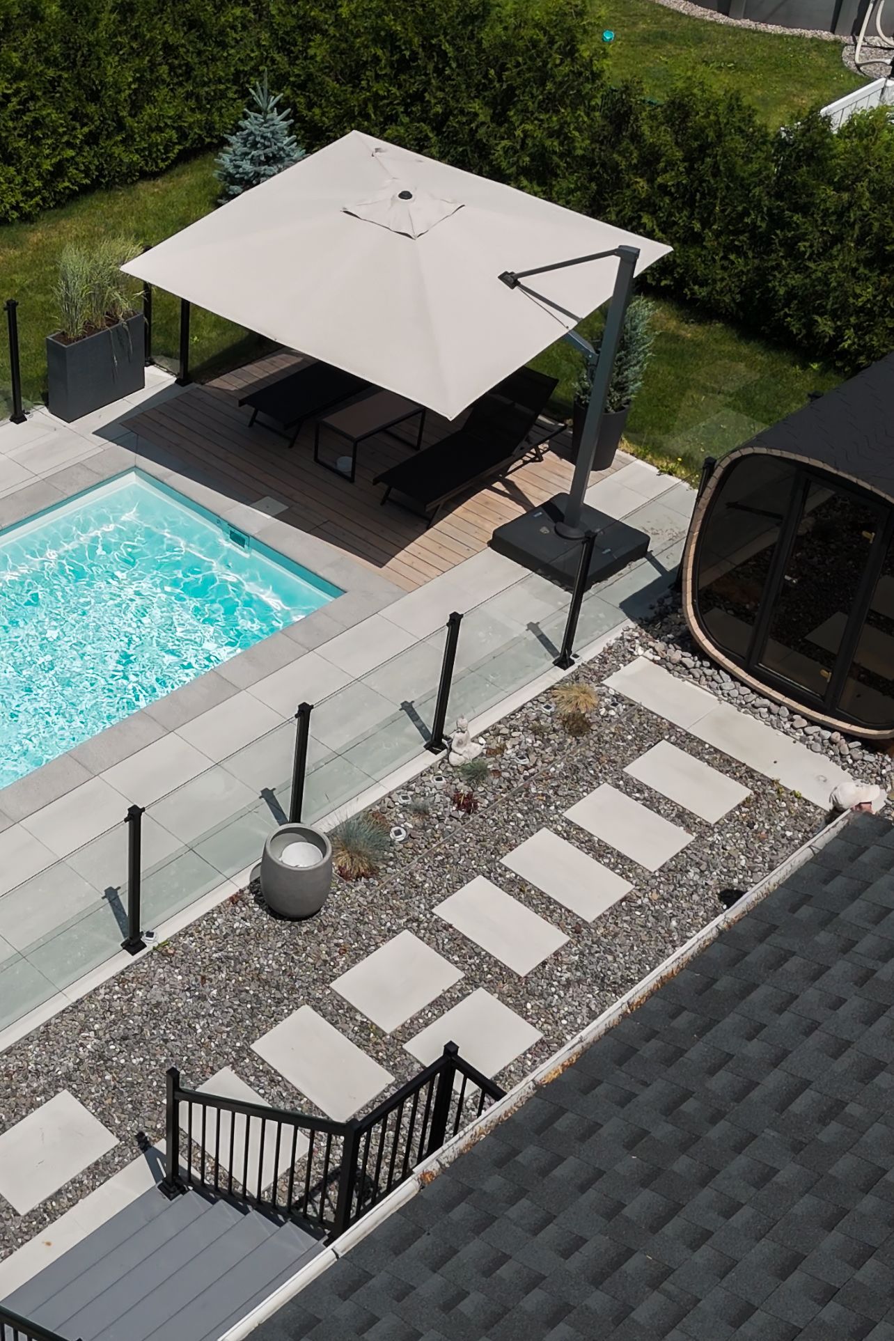 Canapé d'angle gris en forme de L avec table basse assortie sur une terrasse dans un jardin gazonné avec une cabane pour enfants.