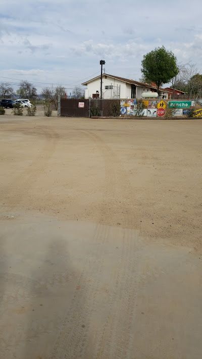 A large dirt field with a house in the background.