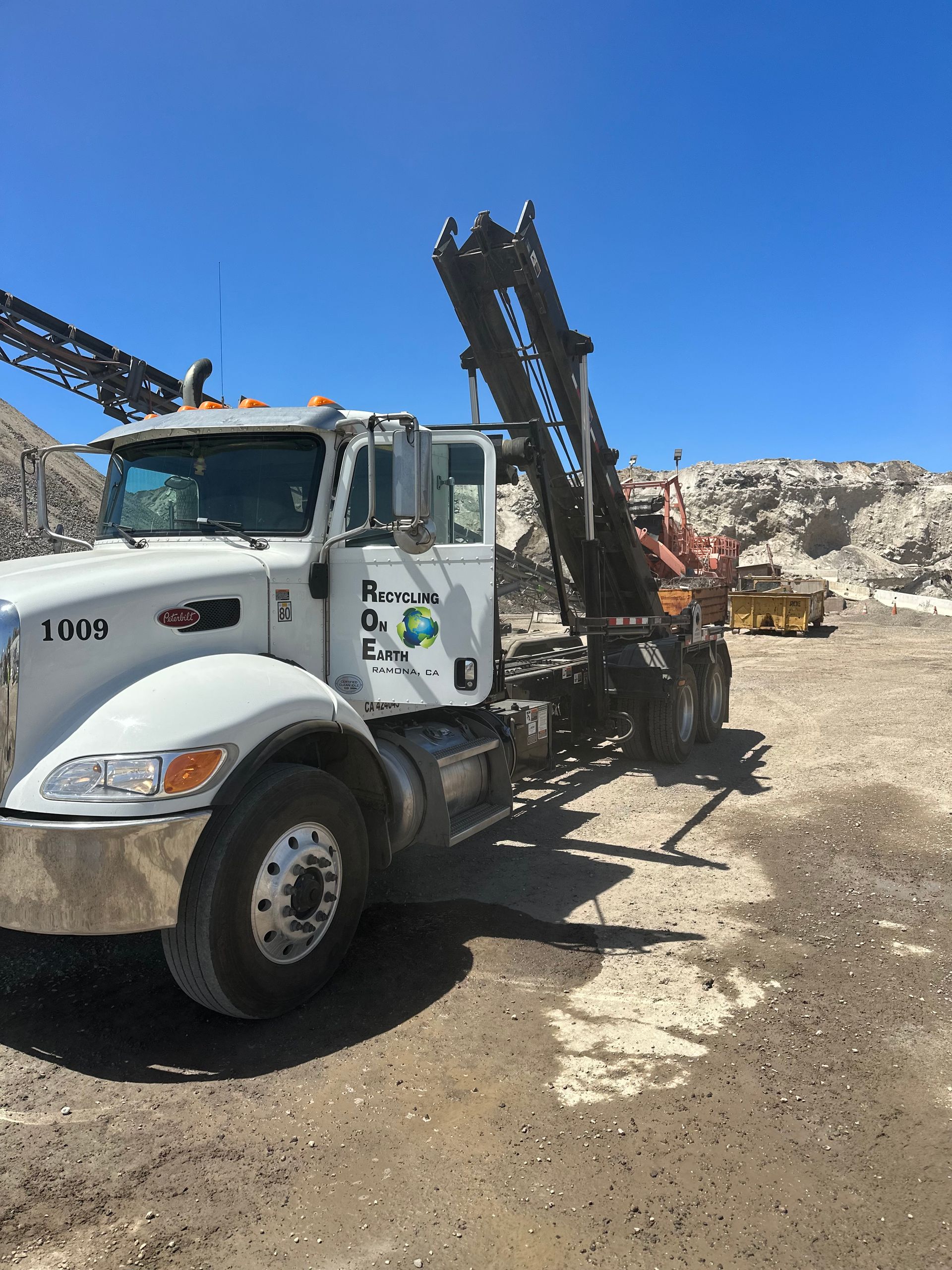 A white dump truck is parked in a dirt field.
