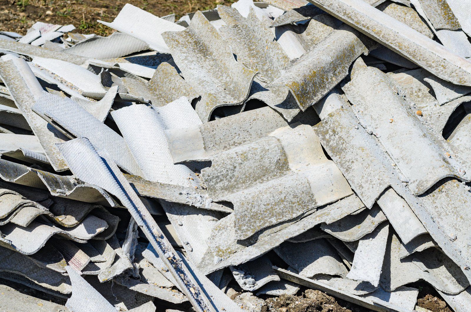 Pile of gray, corrugated asbestos roofing material.