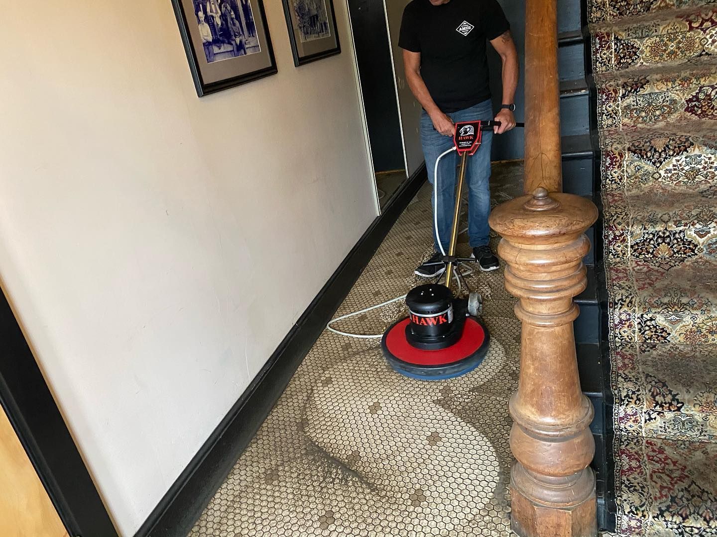A man is cleaning an old tile floor with a machine.