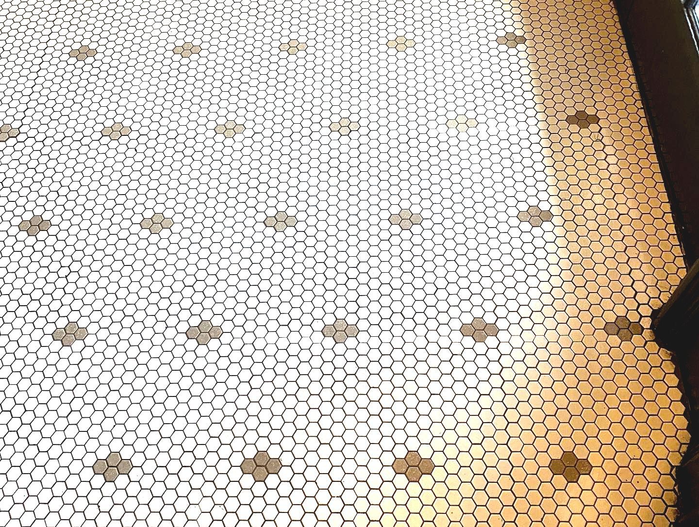 A close up of a white tile floor with black dots.