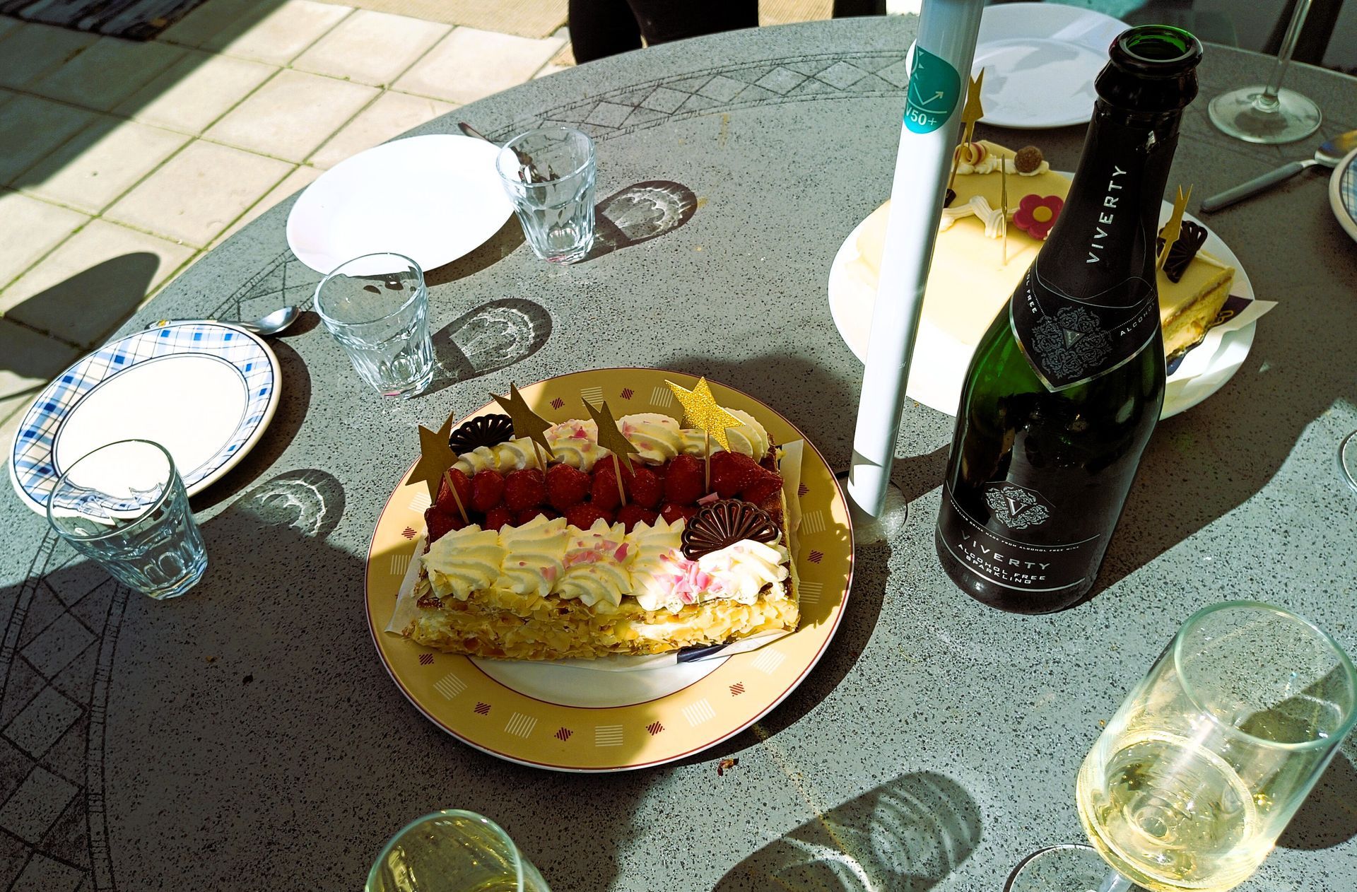 Een fles kinderchampagne staat op een tafel naast een bord met taart