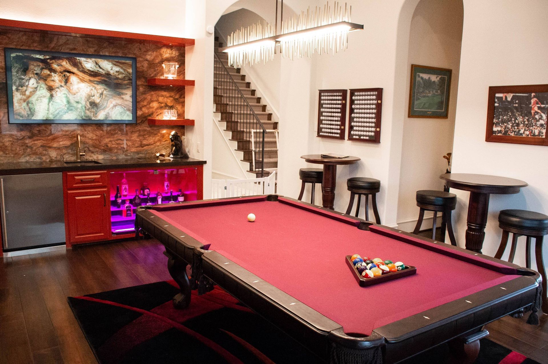 A pool table in a room with stairs in the background