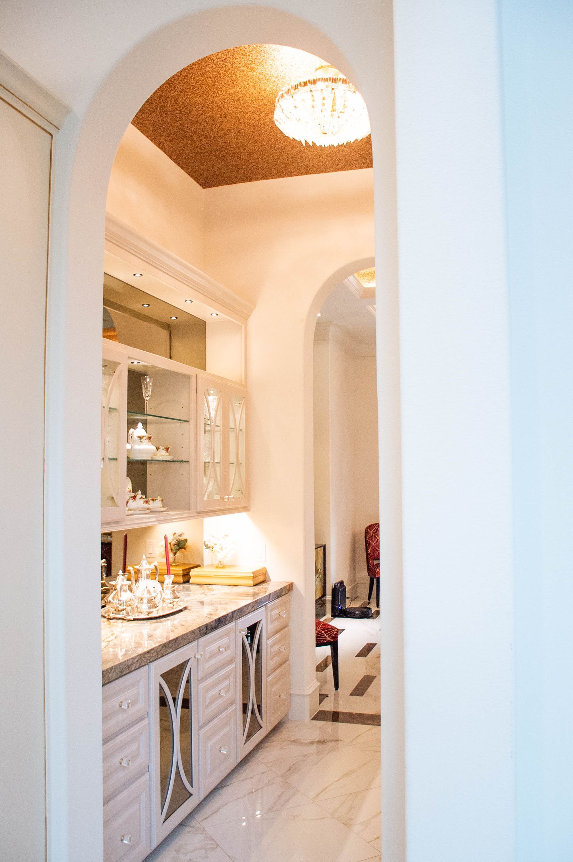 A kitchen with white cabinets and a chandelier on the ceiling.