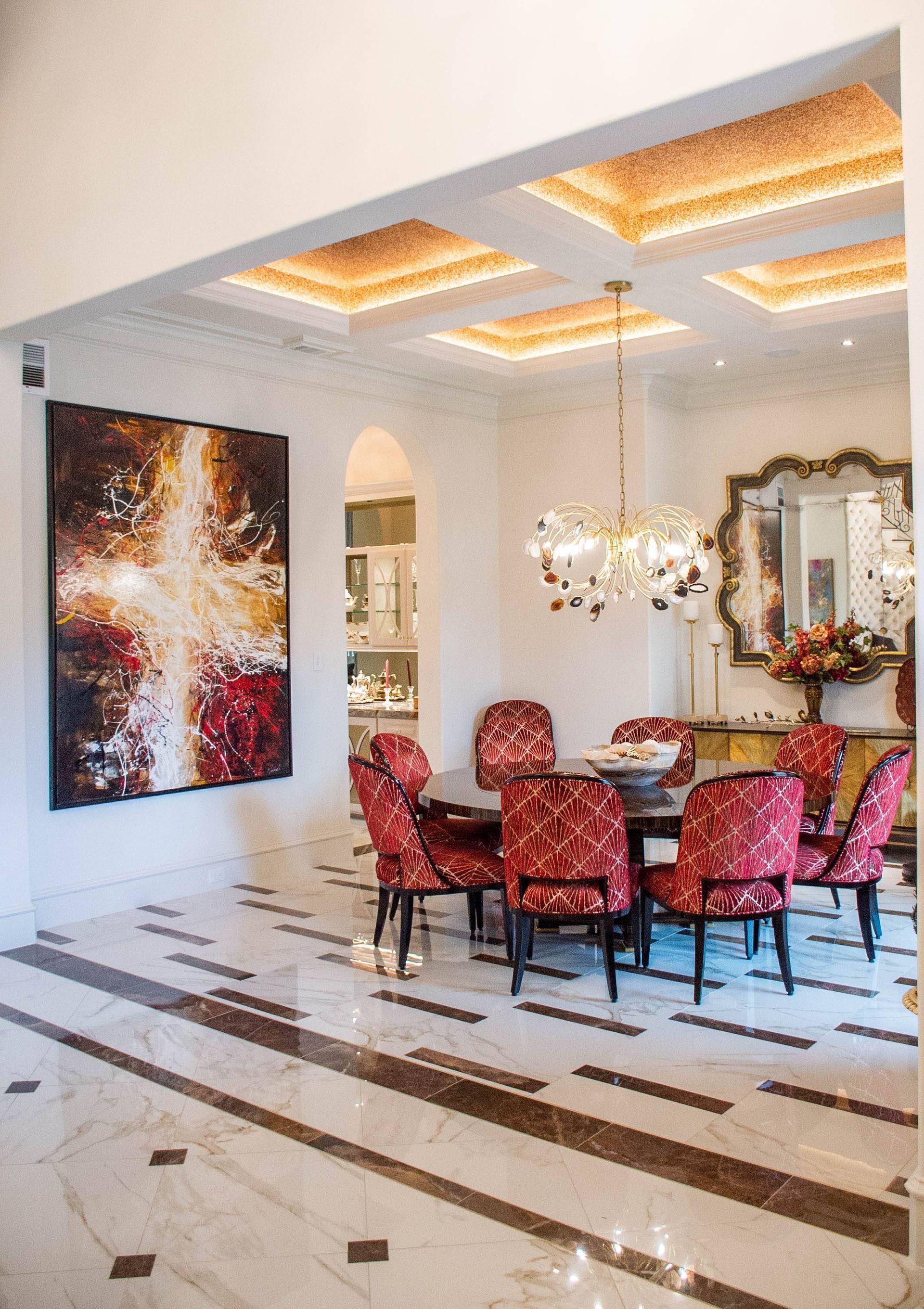 A dining room with a table and chairs and a painting on the wall.