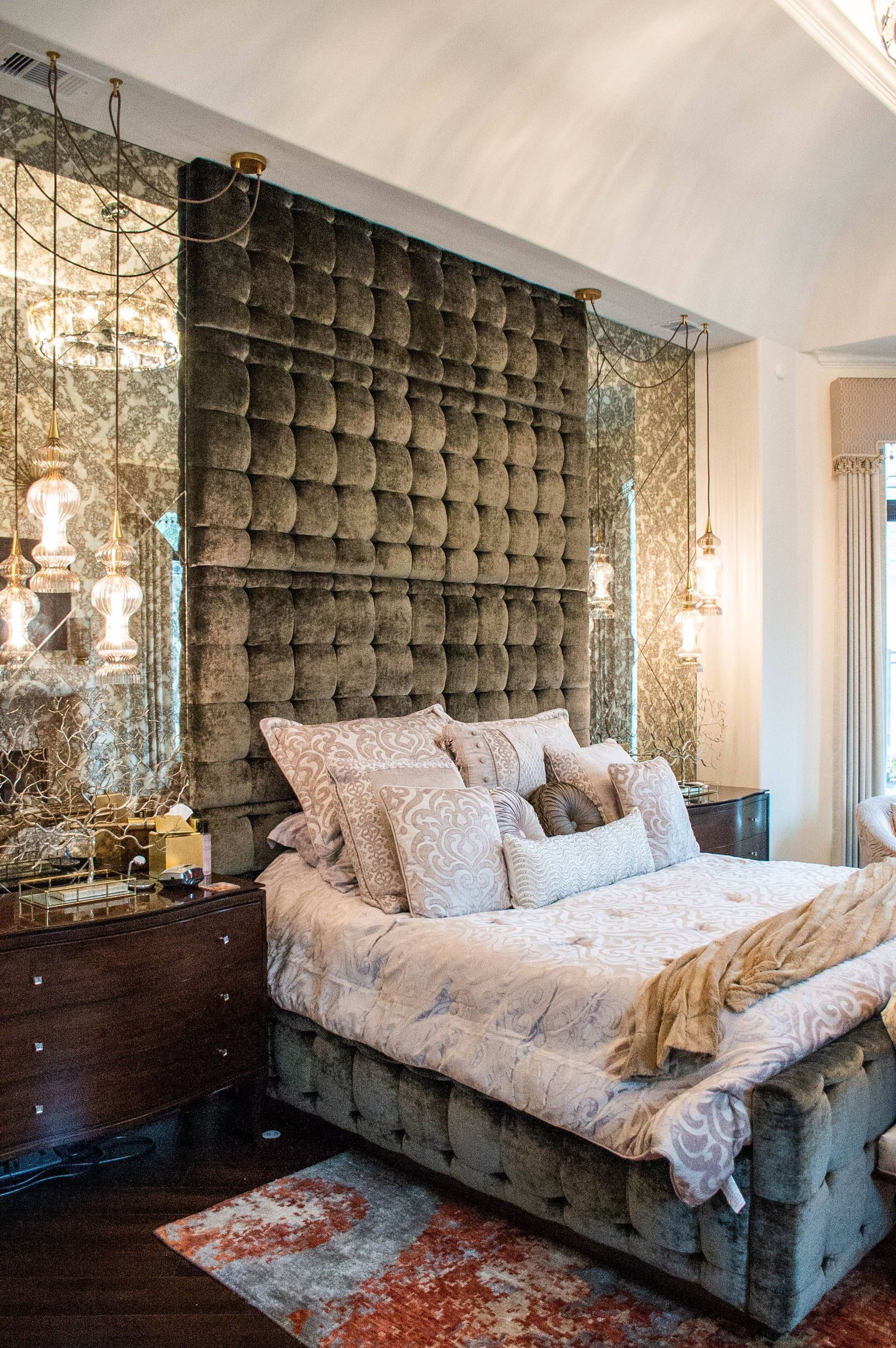 A bedroom with a large bed and a mirrored wall.