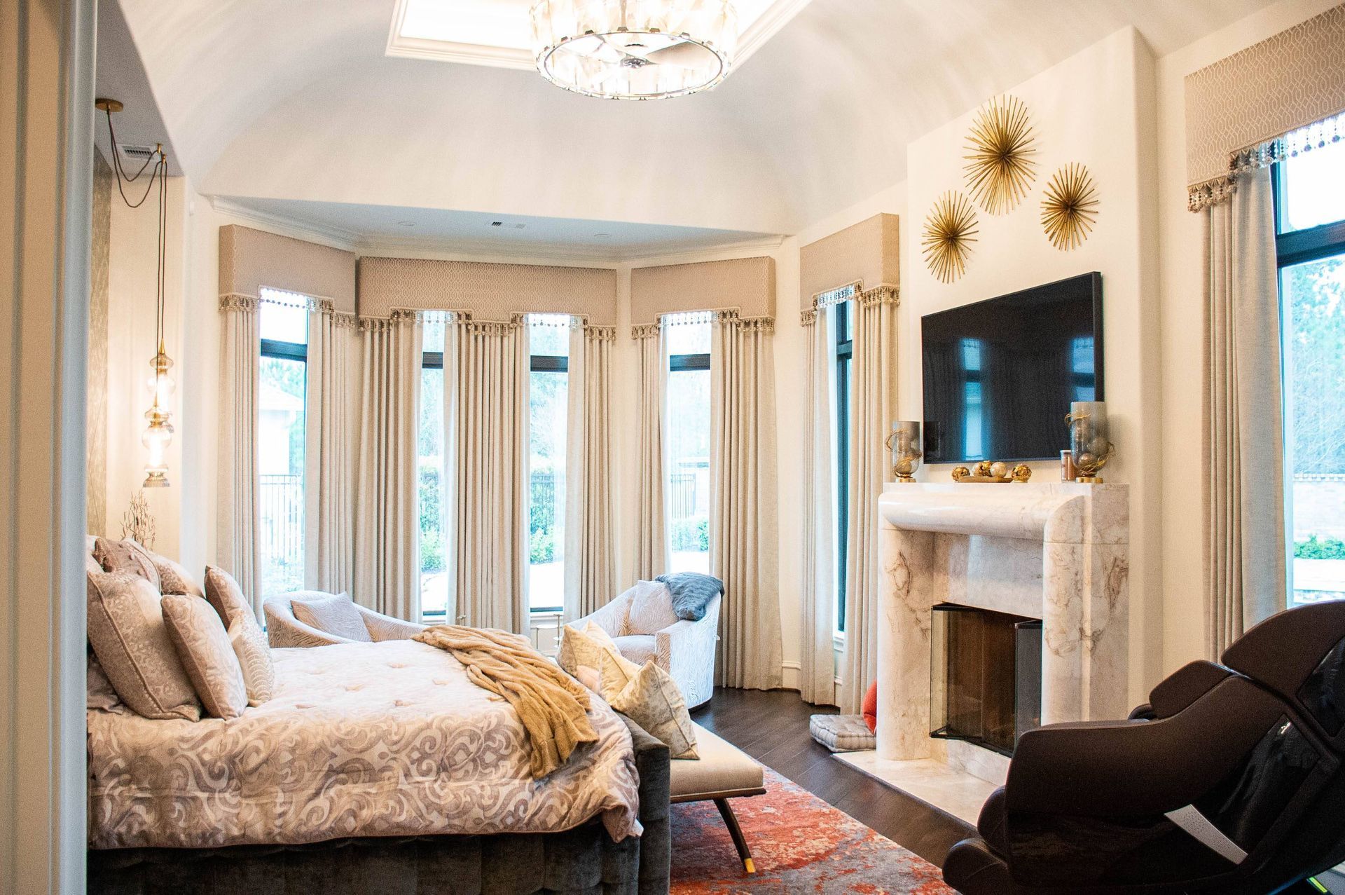 A bedroom with a large bed , fireplace , television and chairs.