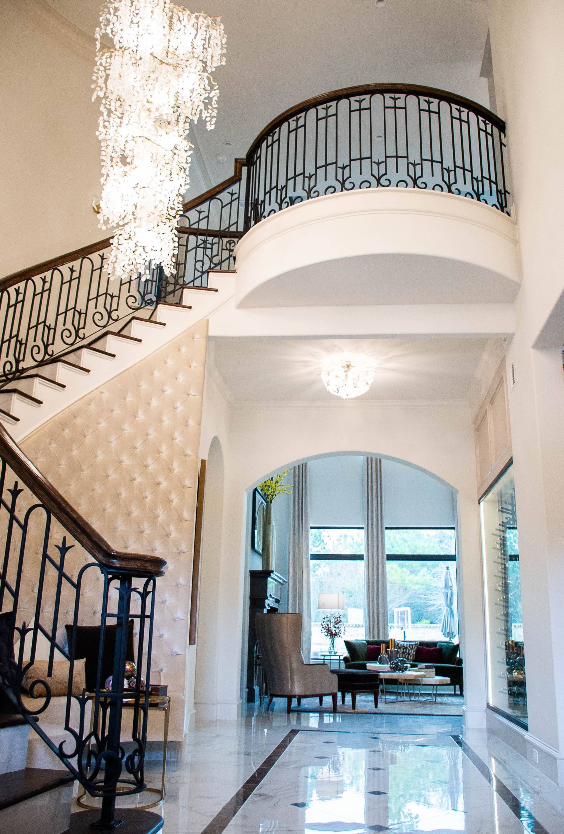 A hallway with a staircase and a chandelier hanging from the ceiling.