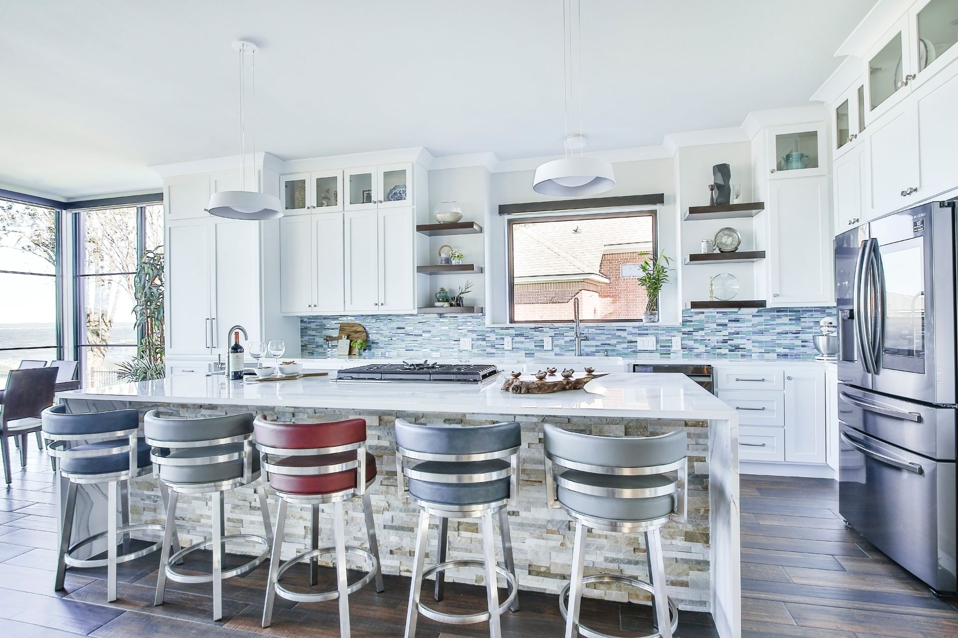 A kitchen with white cabinets , stainless steel appliances , and a large island with stools.
