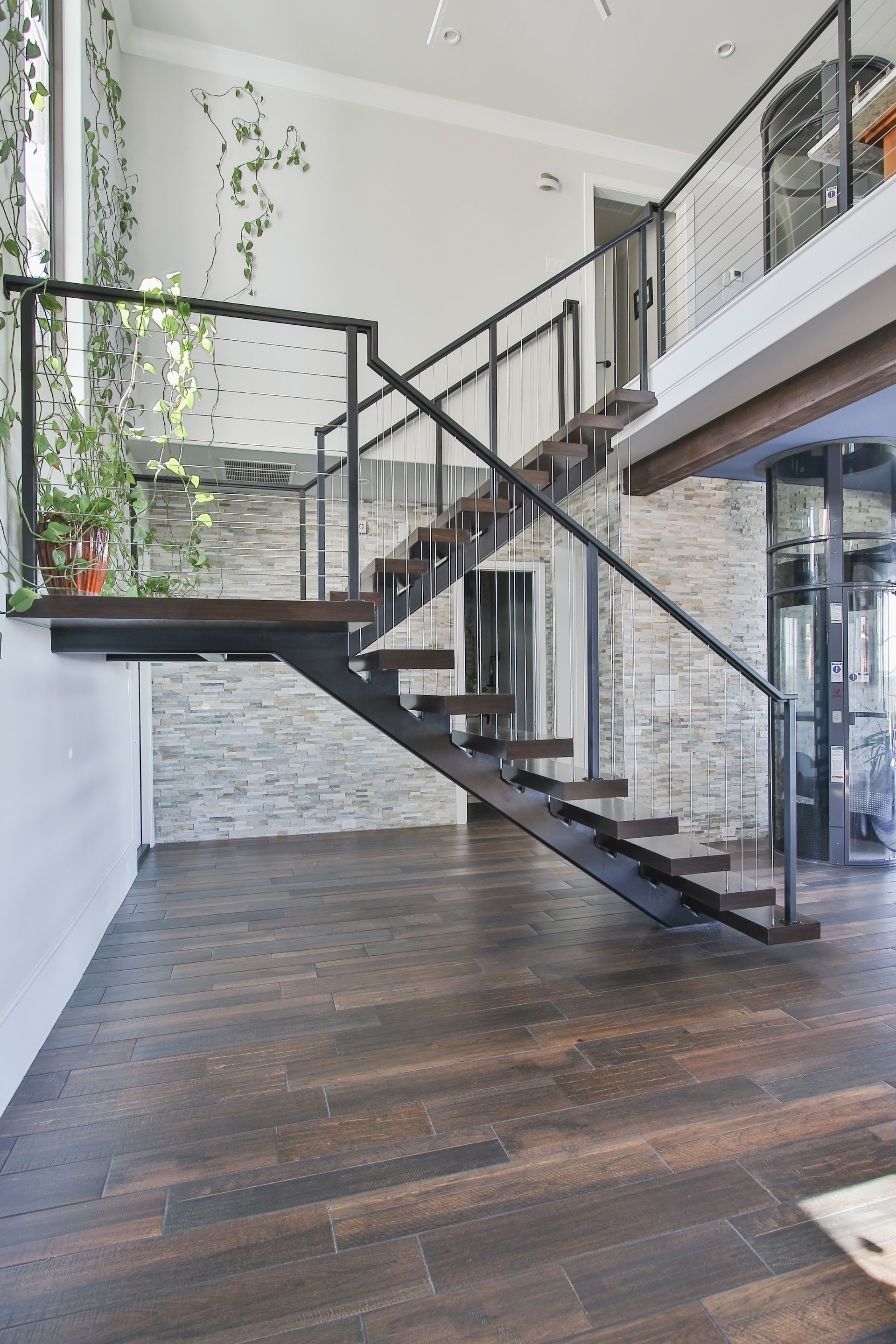A staircase in a house with a wooden floor and a glass railing.