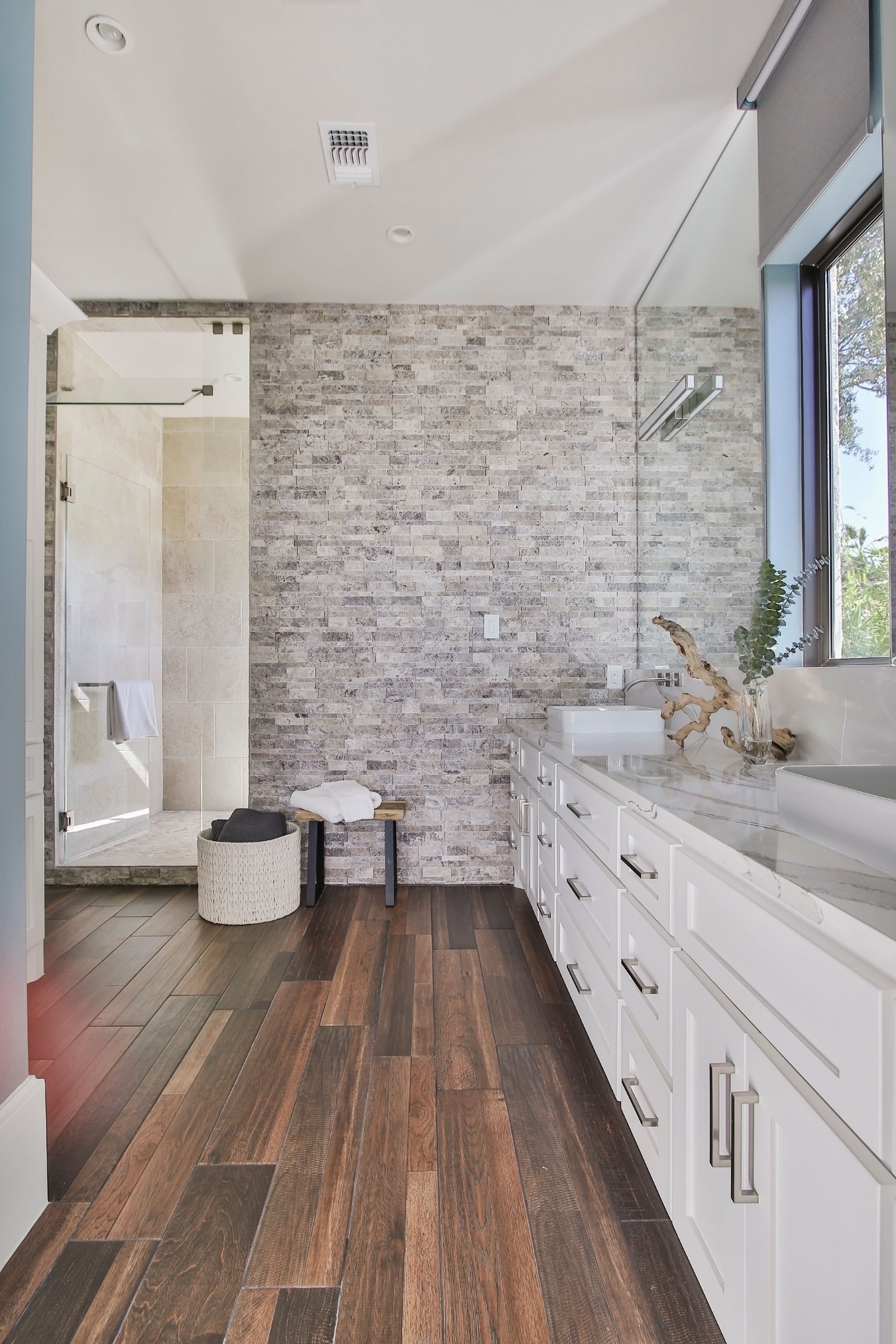 A bathroom with a brick wall , a sink , and a walk in shower.