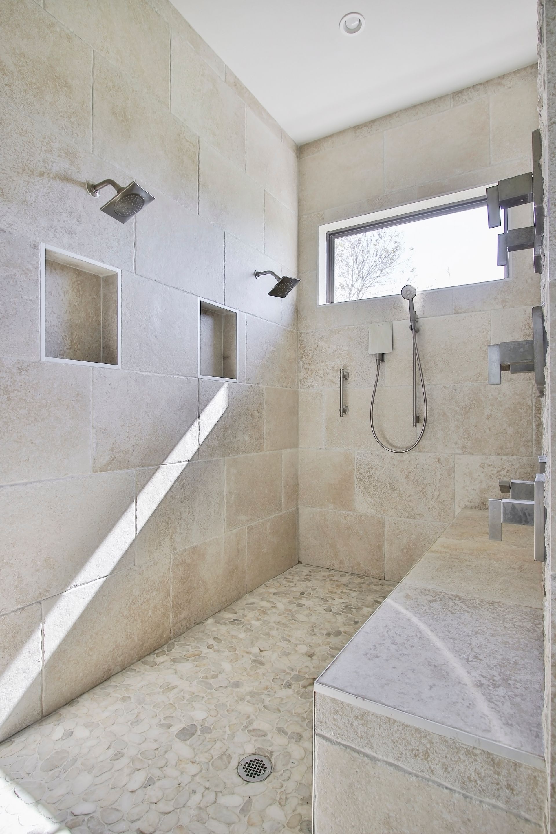 A bathroom with a walk in shower and a window.