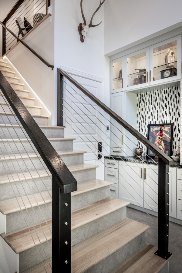 A staircase with a black railing and a deer head on the wall