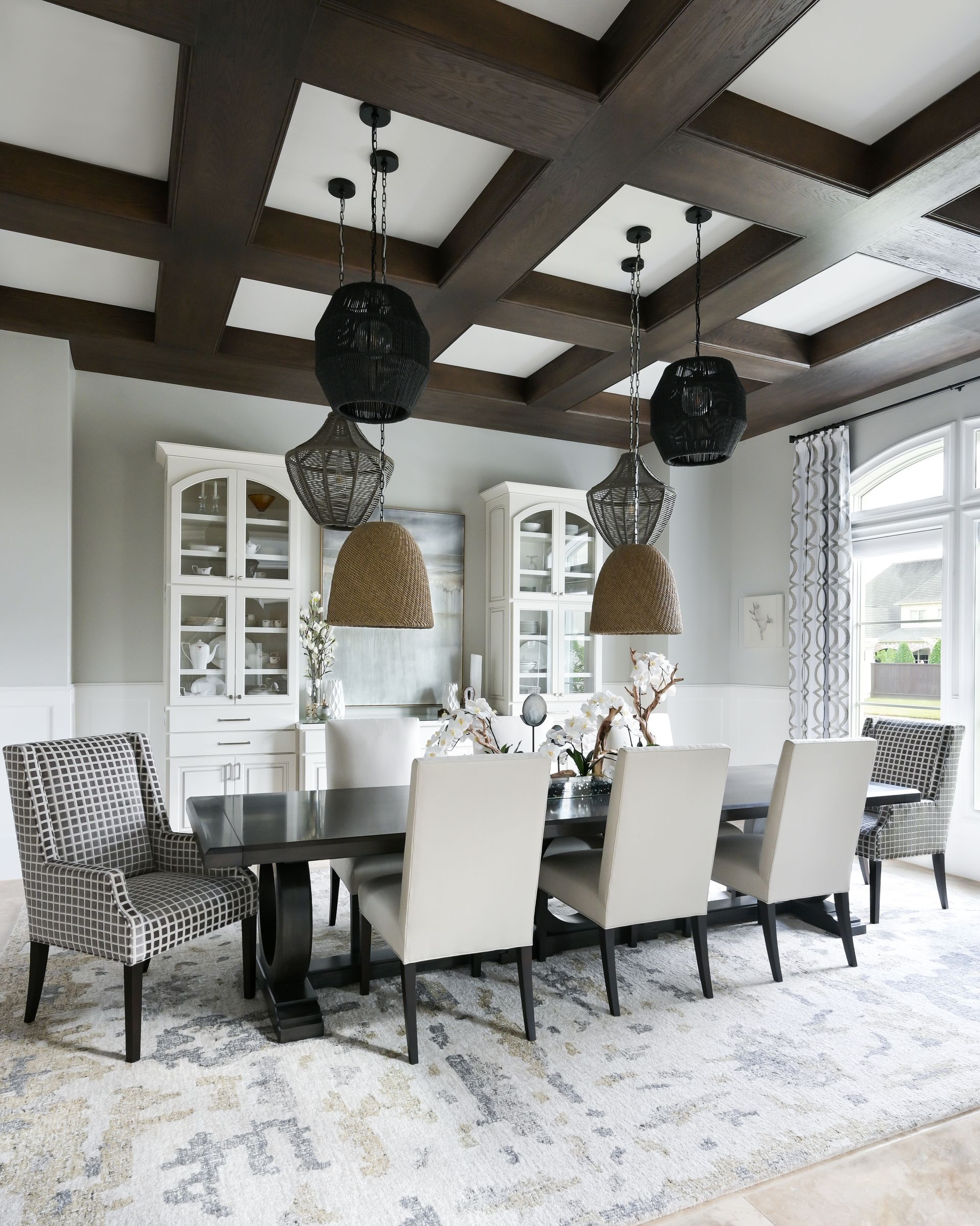 A dining room with a table and chairs and a coffered ceiling.