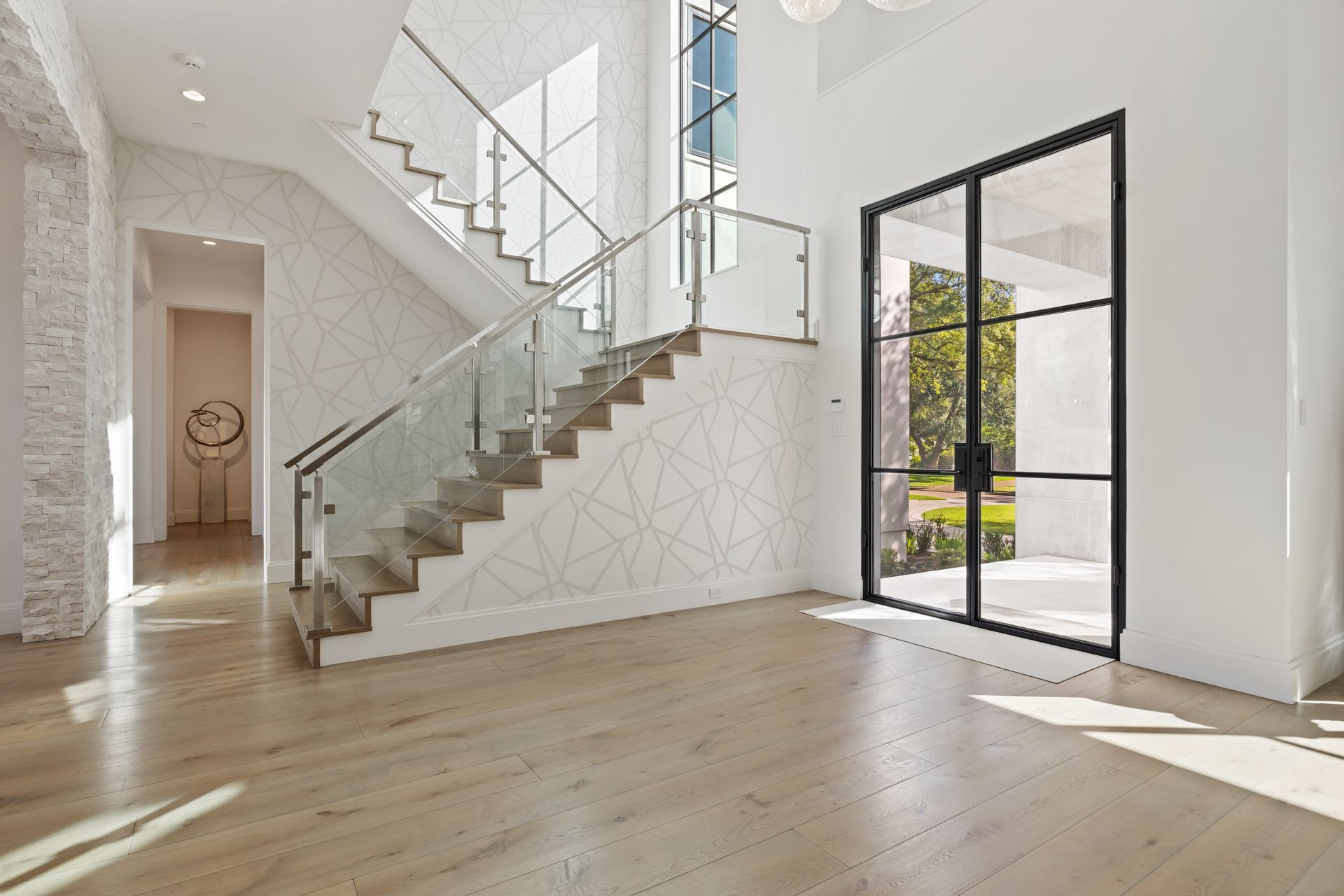 There is a staircase in the middle of the room with a glass railing.