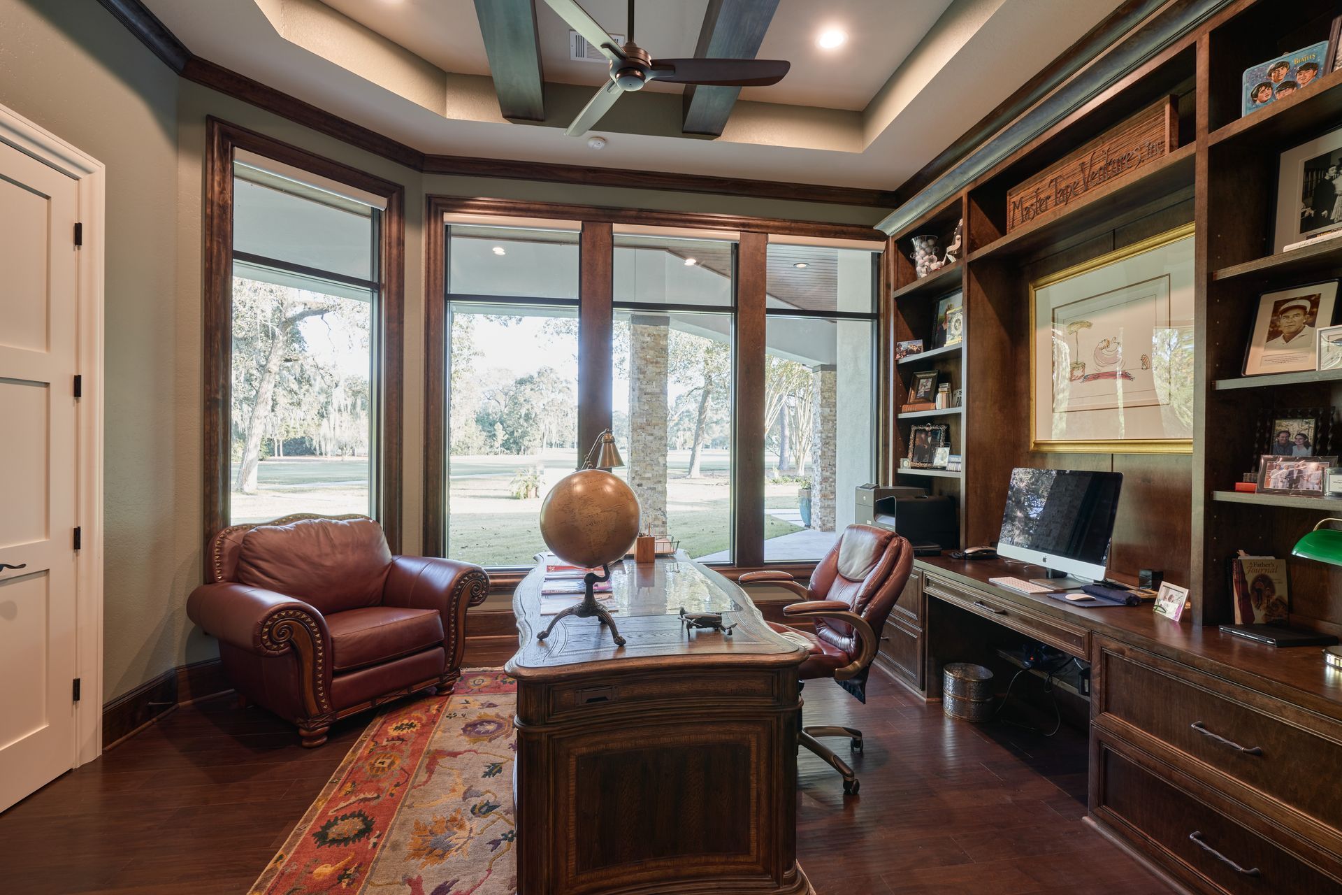 A home office with a desk and chairs and a ceiling fan