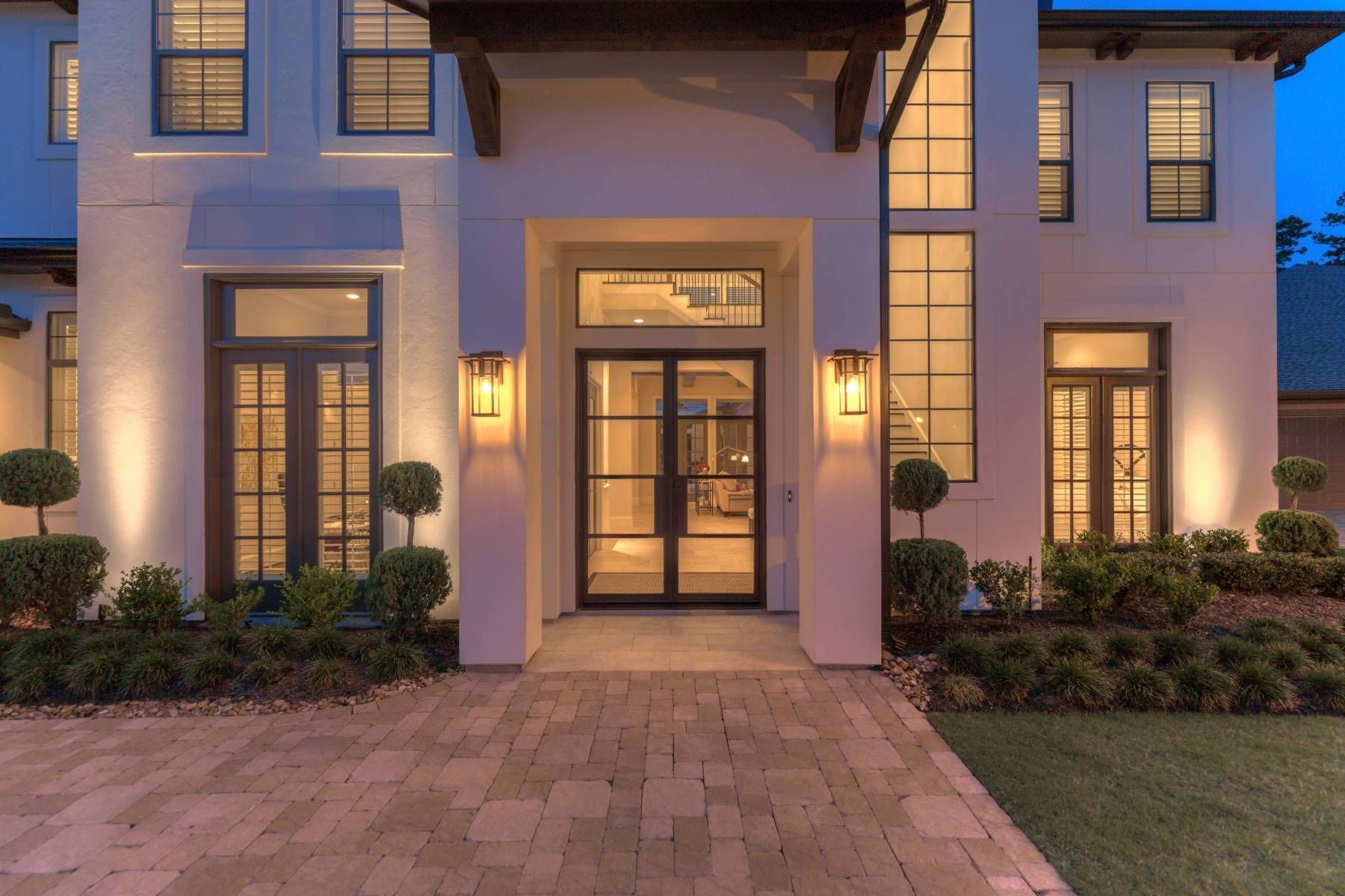 A large white house with a lot of windows and a brick driveway