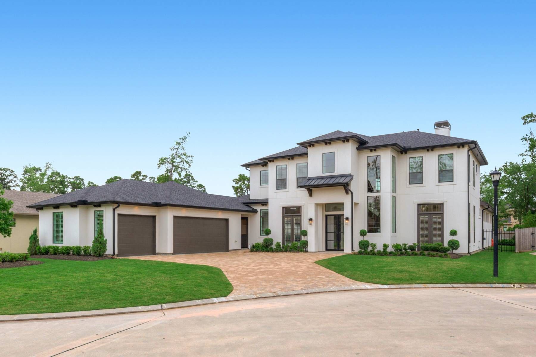 A large white house with two garages is sitting on top of a lush green lawn.
