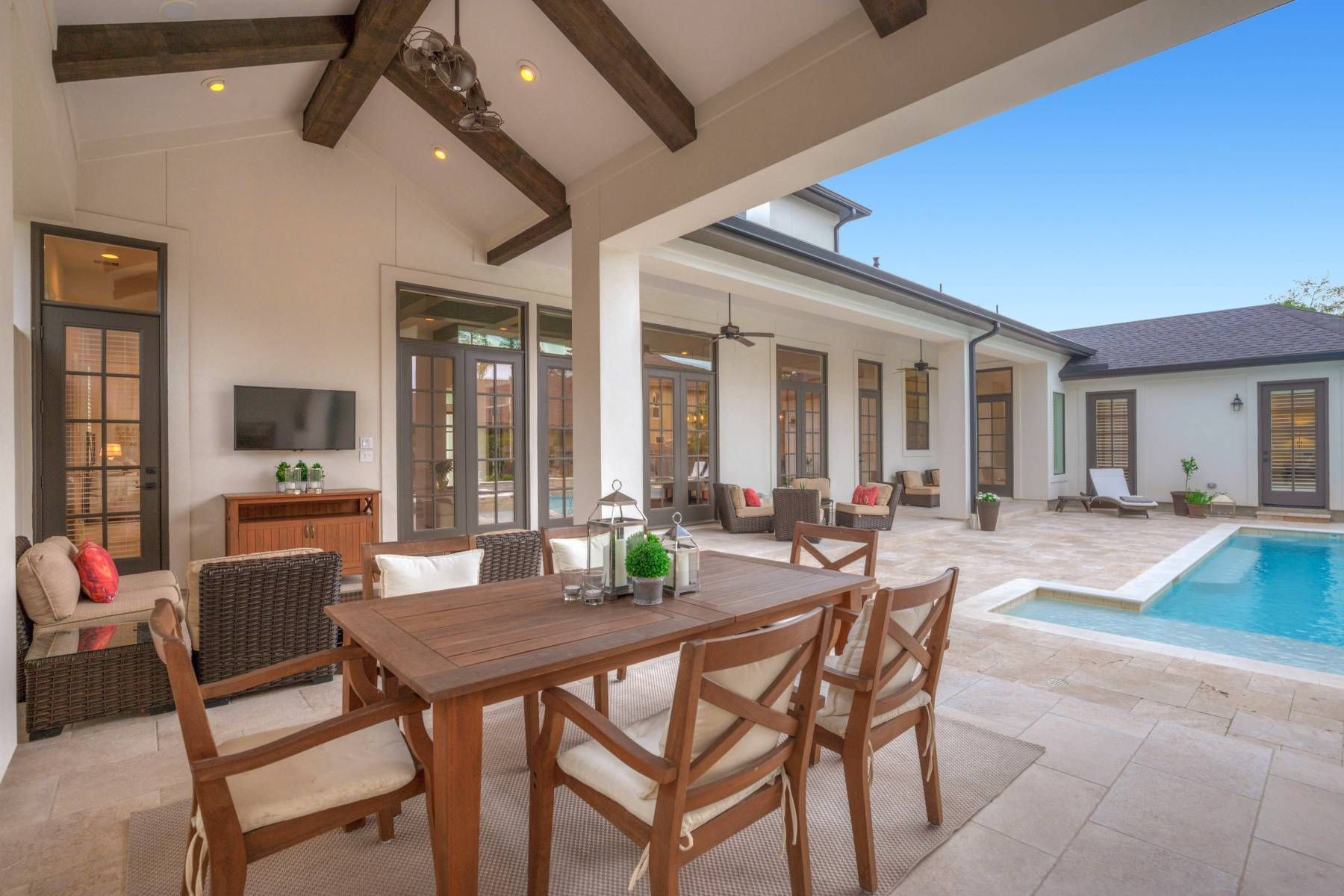 A patio with a table and chairs next to a swimming pool.