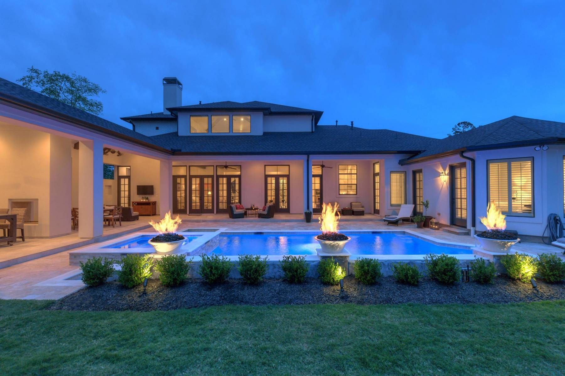 A large house with a large swimming pool in the backyard at night.