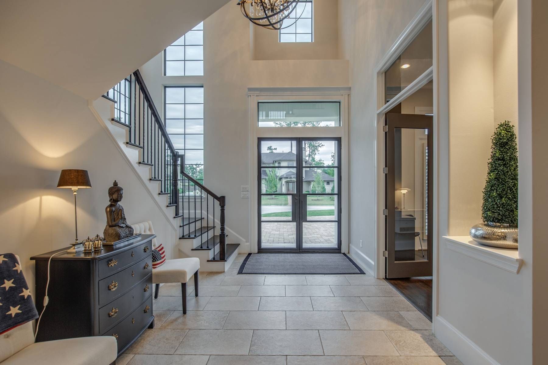 A hallway in a house with a staircase and a dresser