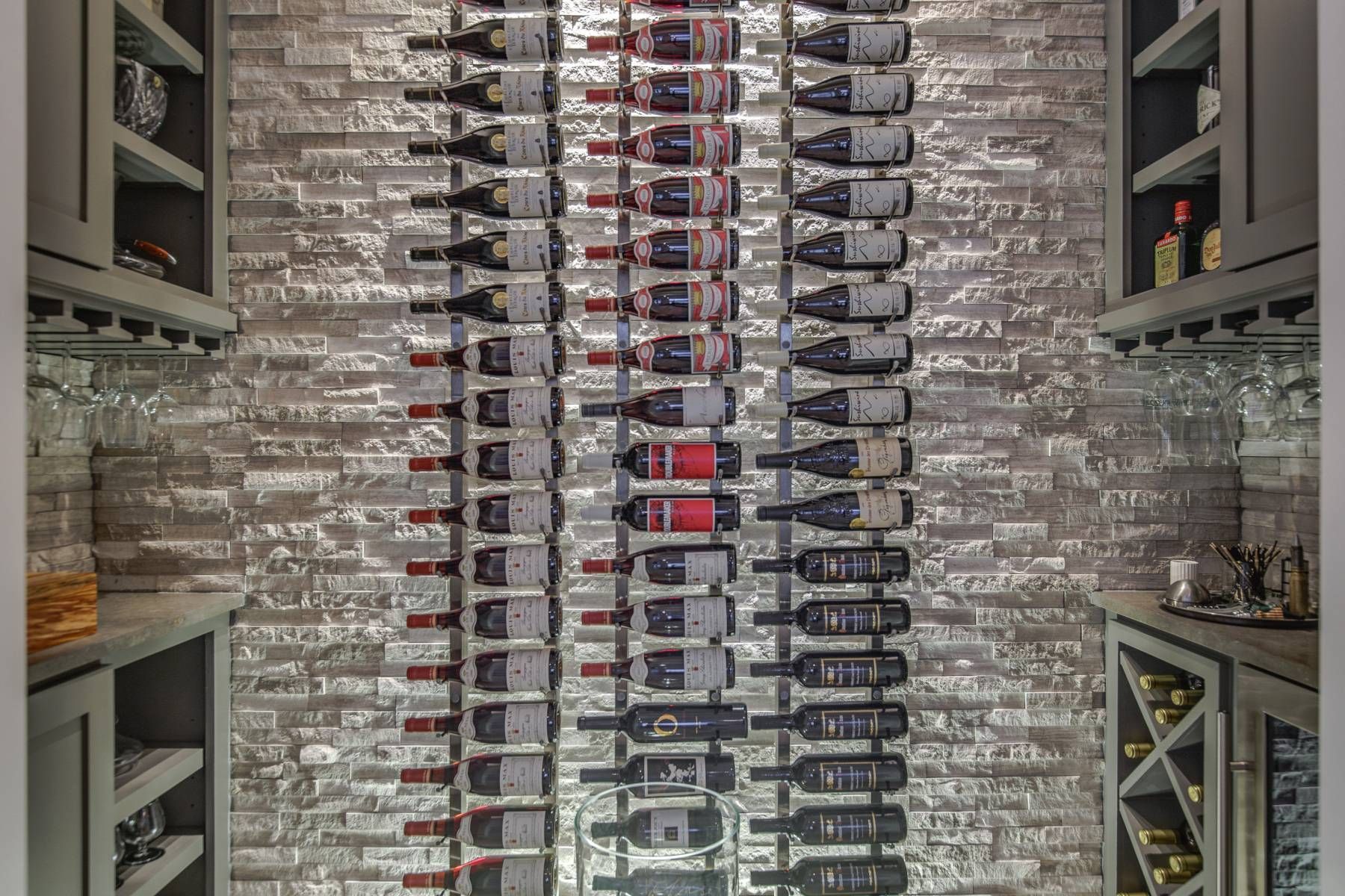 A wine cellar filled with lots of wine bottles and glasses.