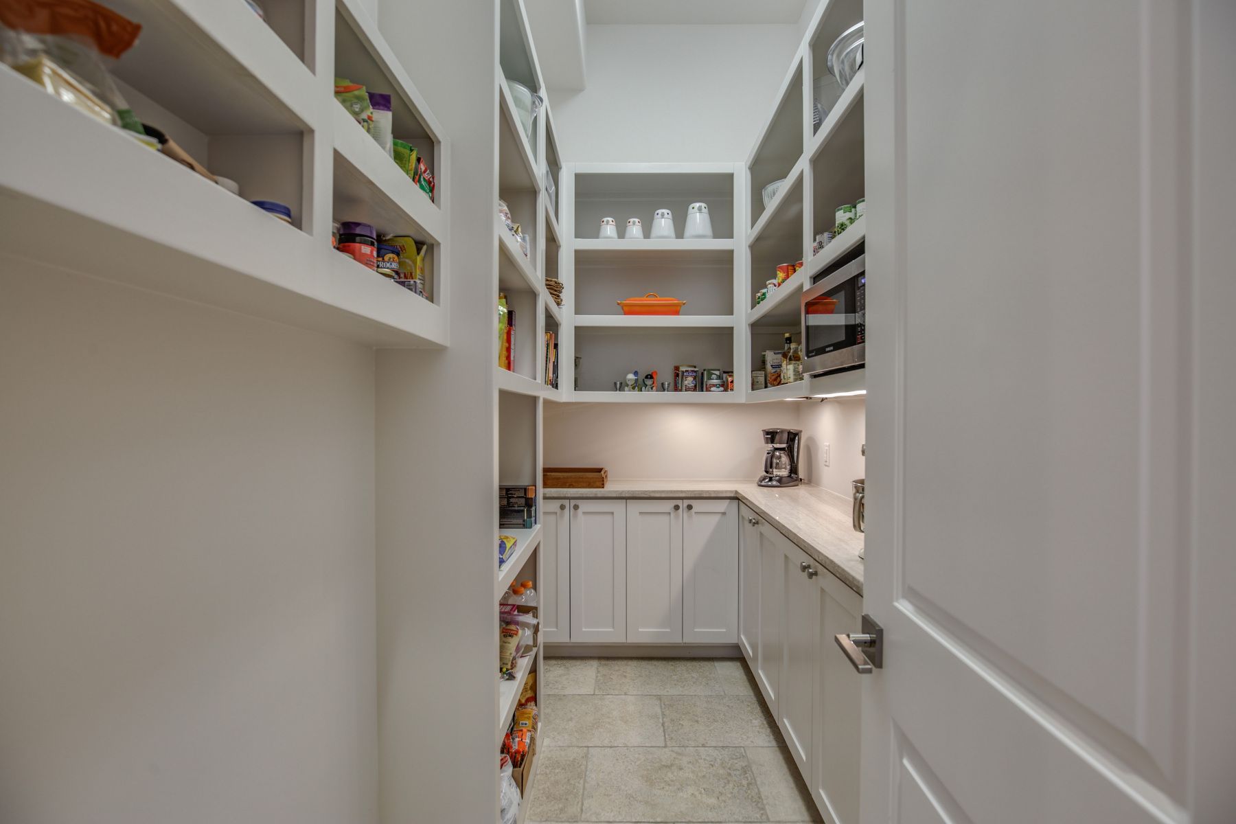 A pantry with lots of shelves and cabinets in a house.