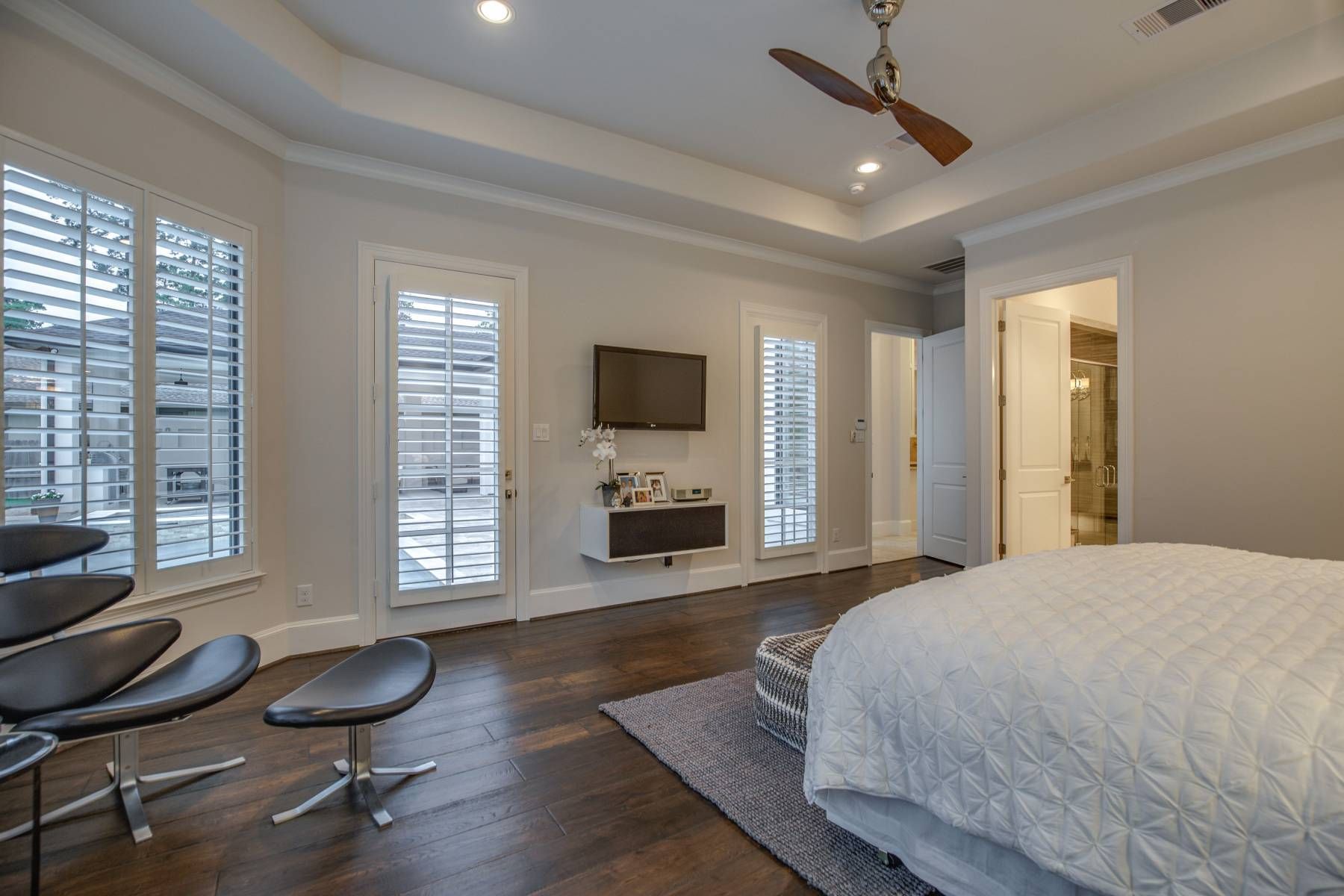 A bedroom with a bed , chair , television and ceiling fan.