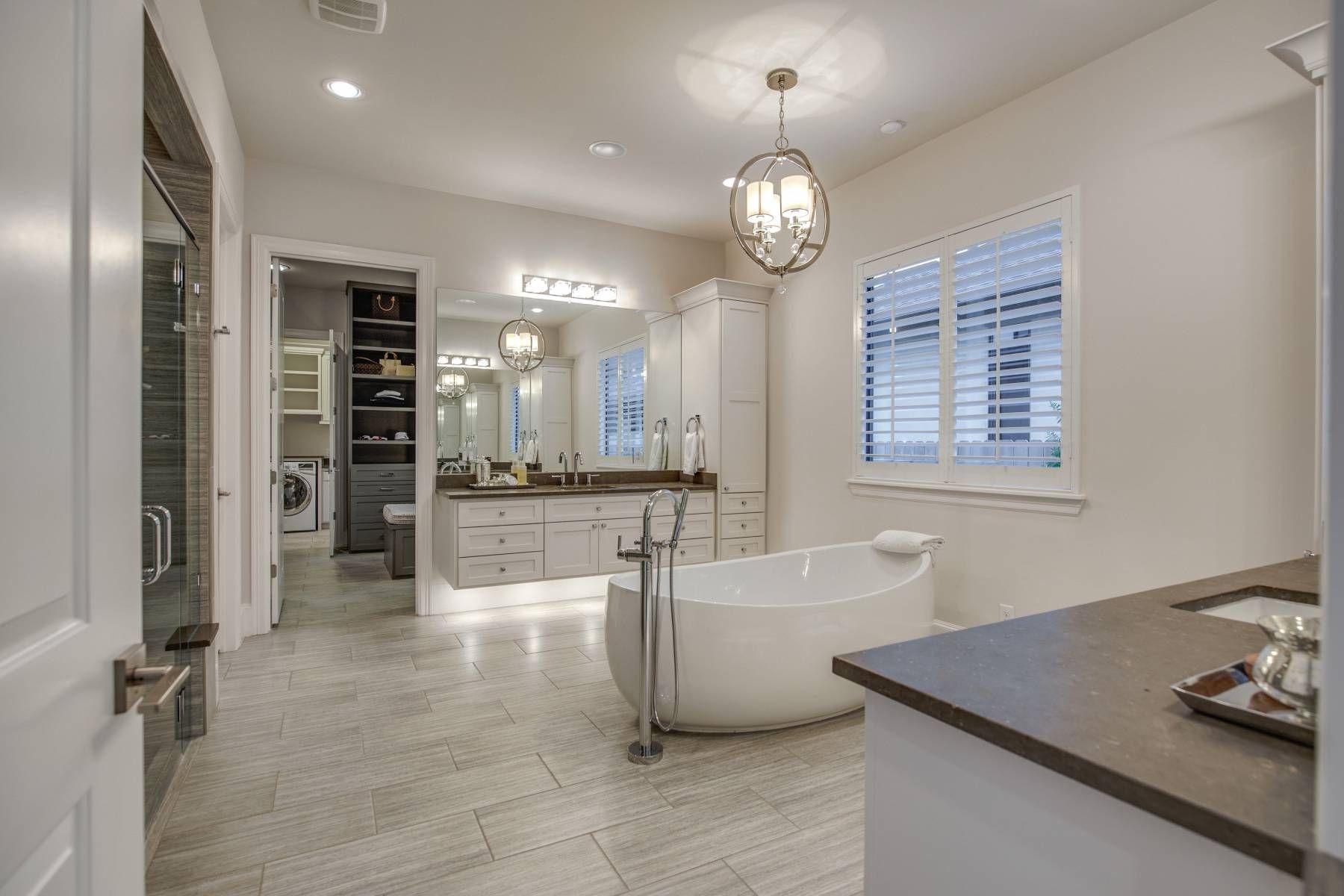 A large bathroom with a bathtub , sink , mirrors and shutters.