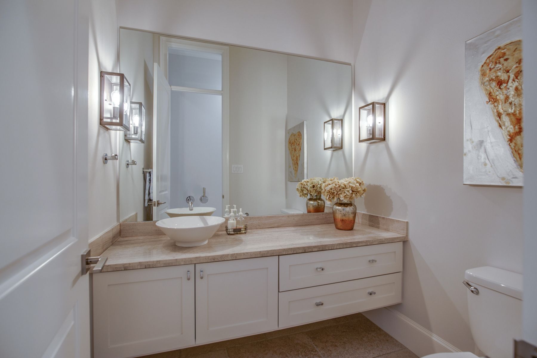 A bathroom with two sinks , a toilet and a large mirror.