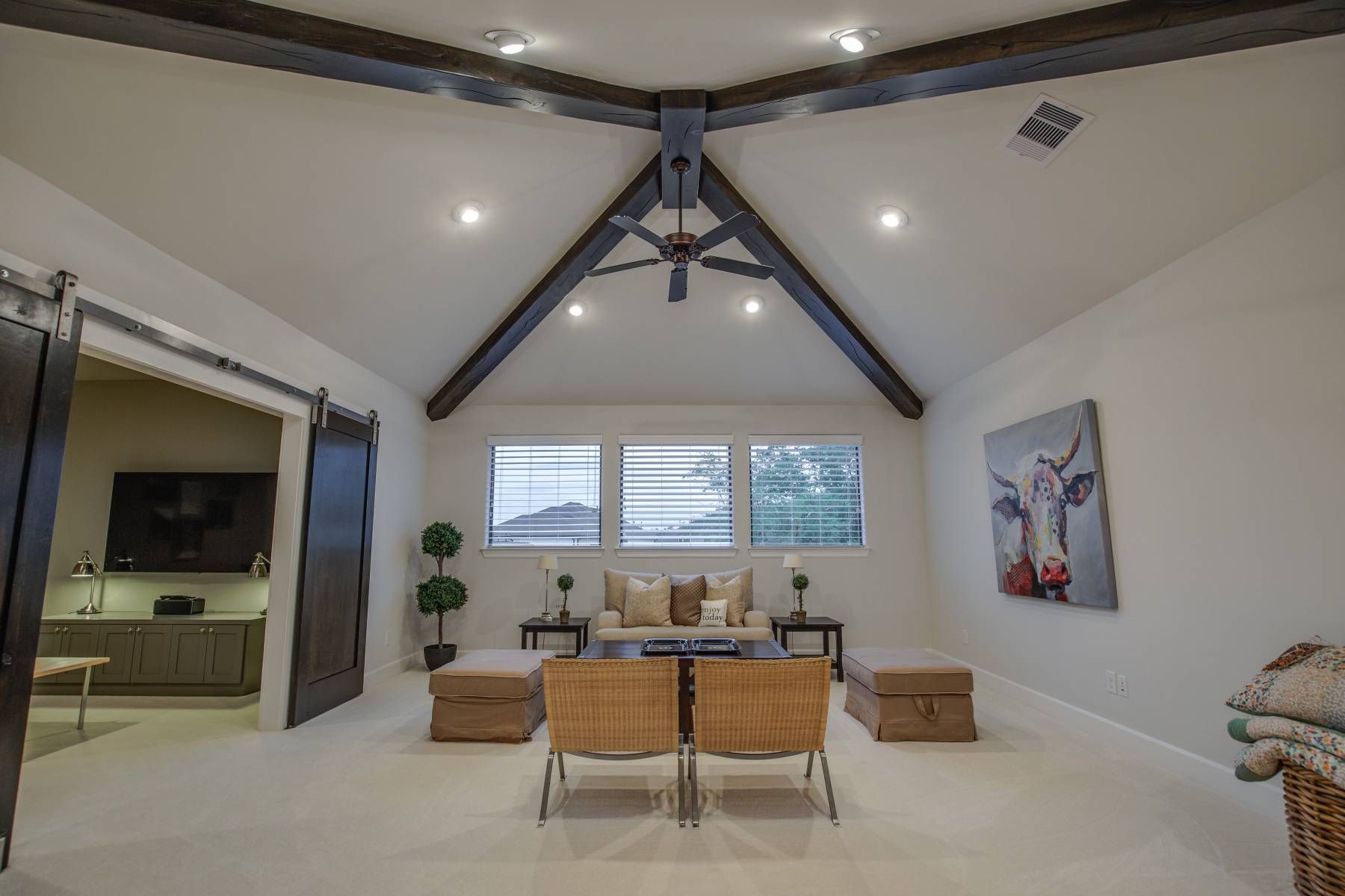 A living room with a vaulted ceiling and a painting of a cow on the wall.