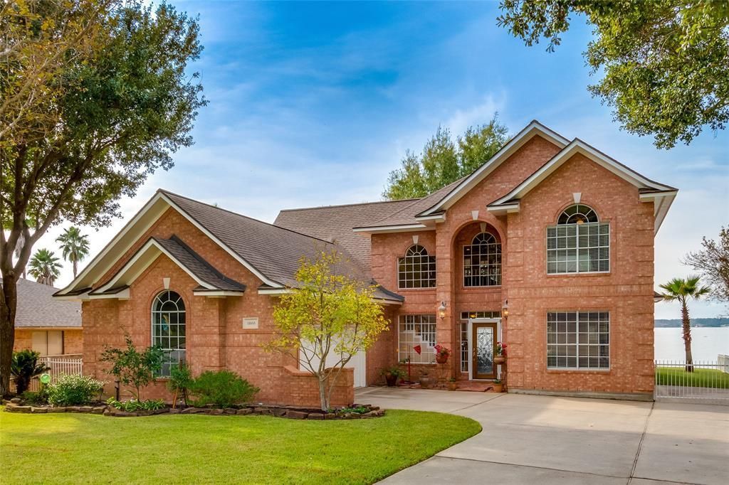 A large brick house sits next to a lake