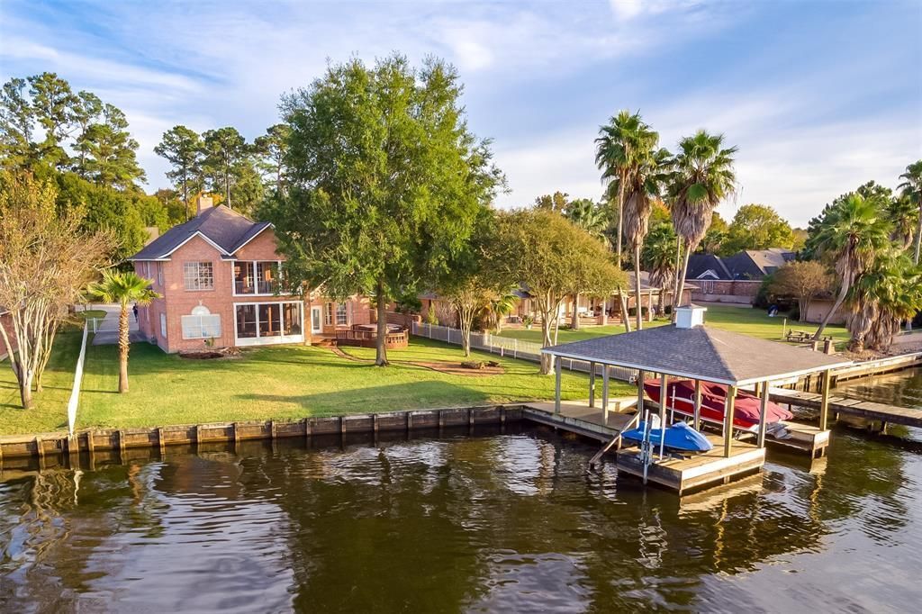 A house is sitting on the shore of a body of water next to a dock.