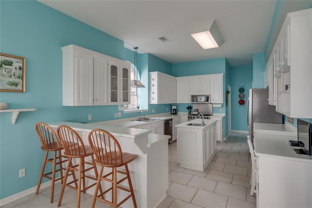 A kitchen with blue walls and white cabinets and stools
