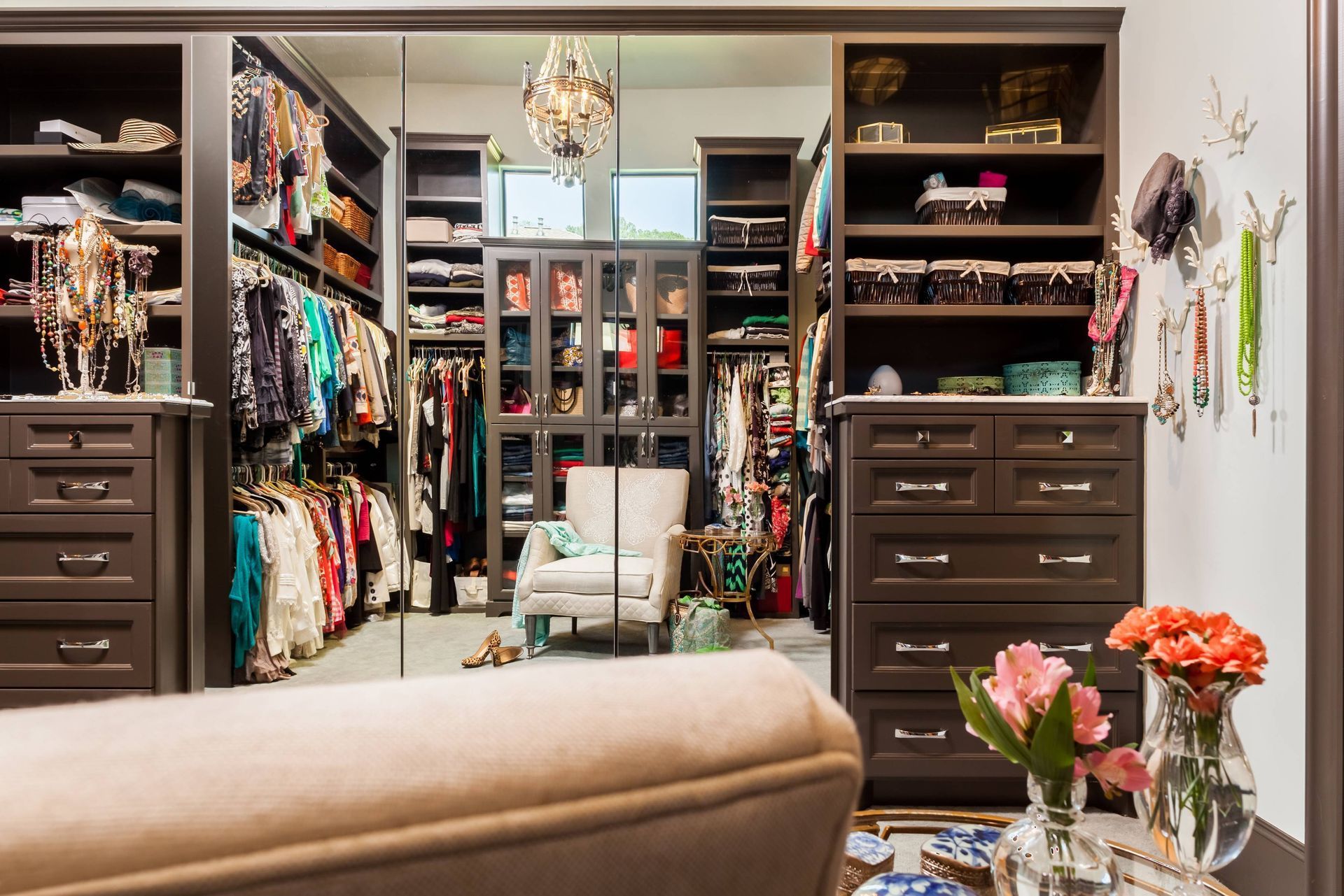 A walk in closet with lots of clothes and a couch.