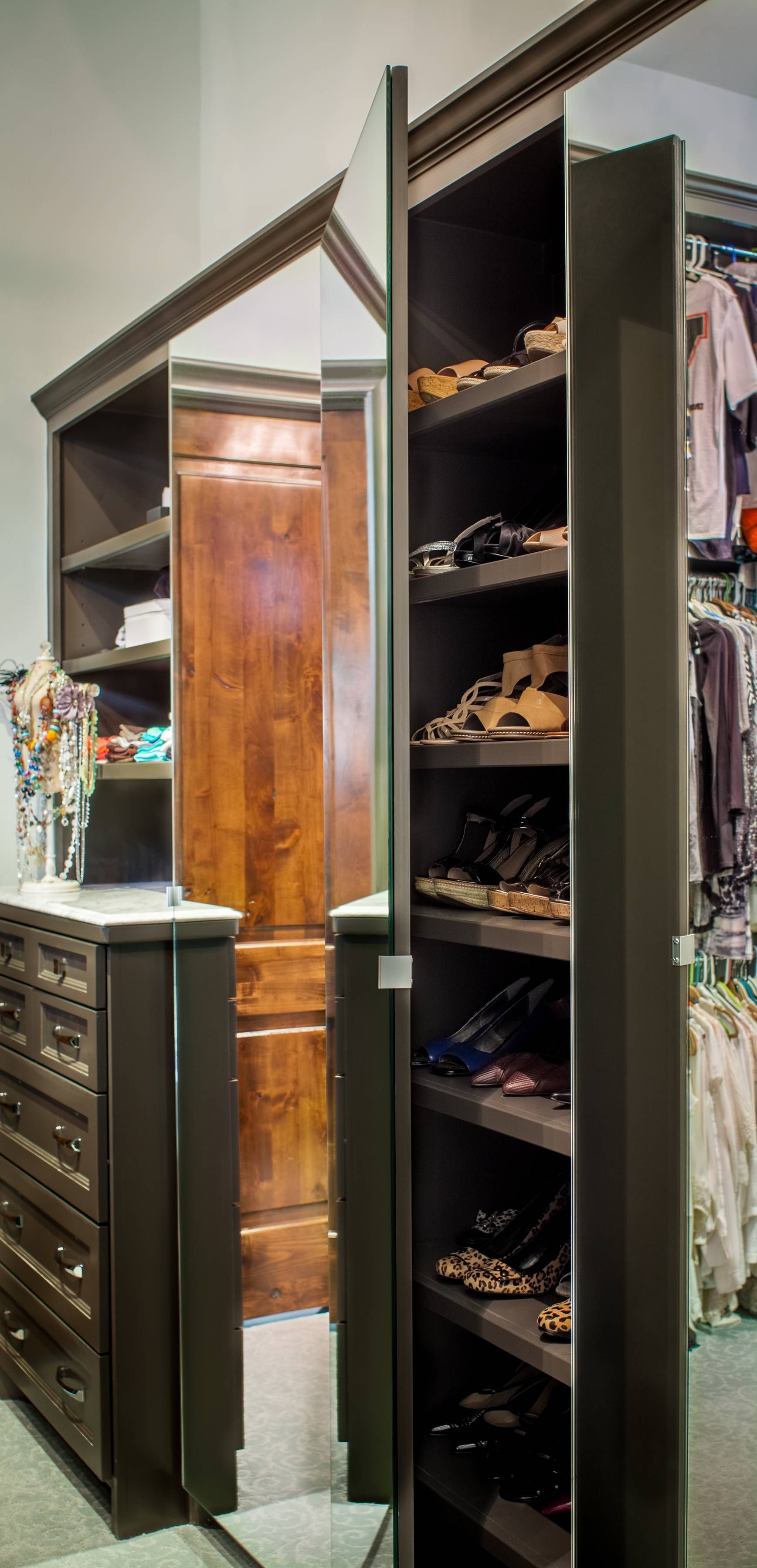 A walk in closet with a mirror and shelves filled with shoes.