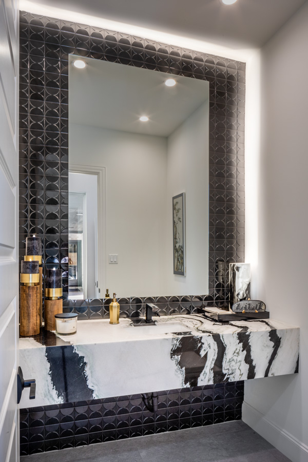 A bathroom with a large mirror and a marble counter top.