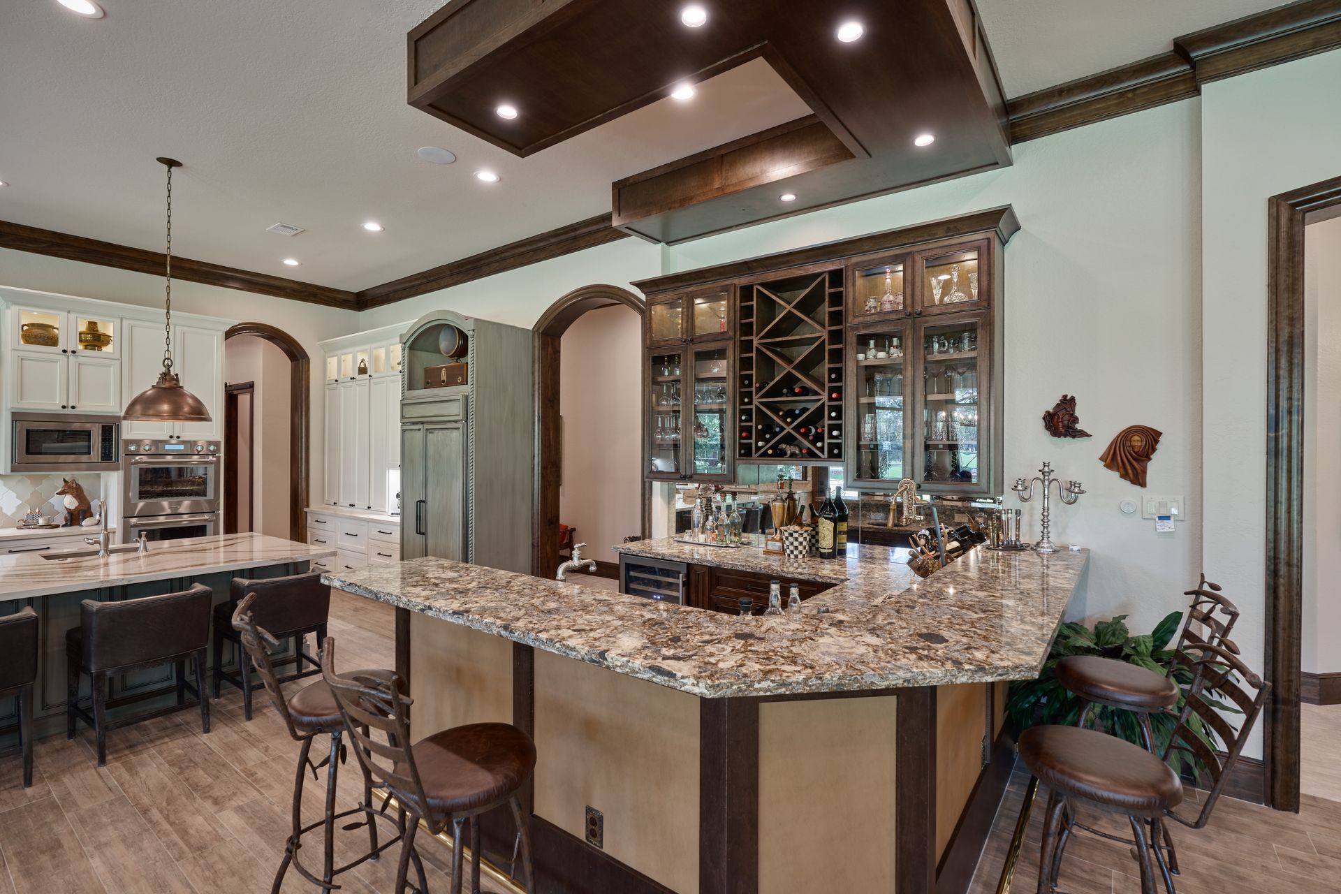 A kitchen with a large granite counter top and stools.