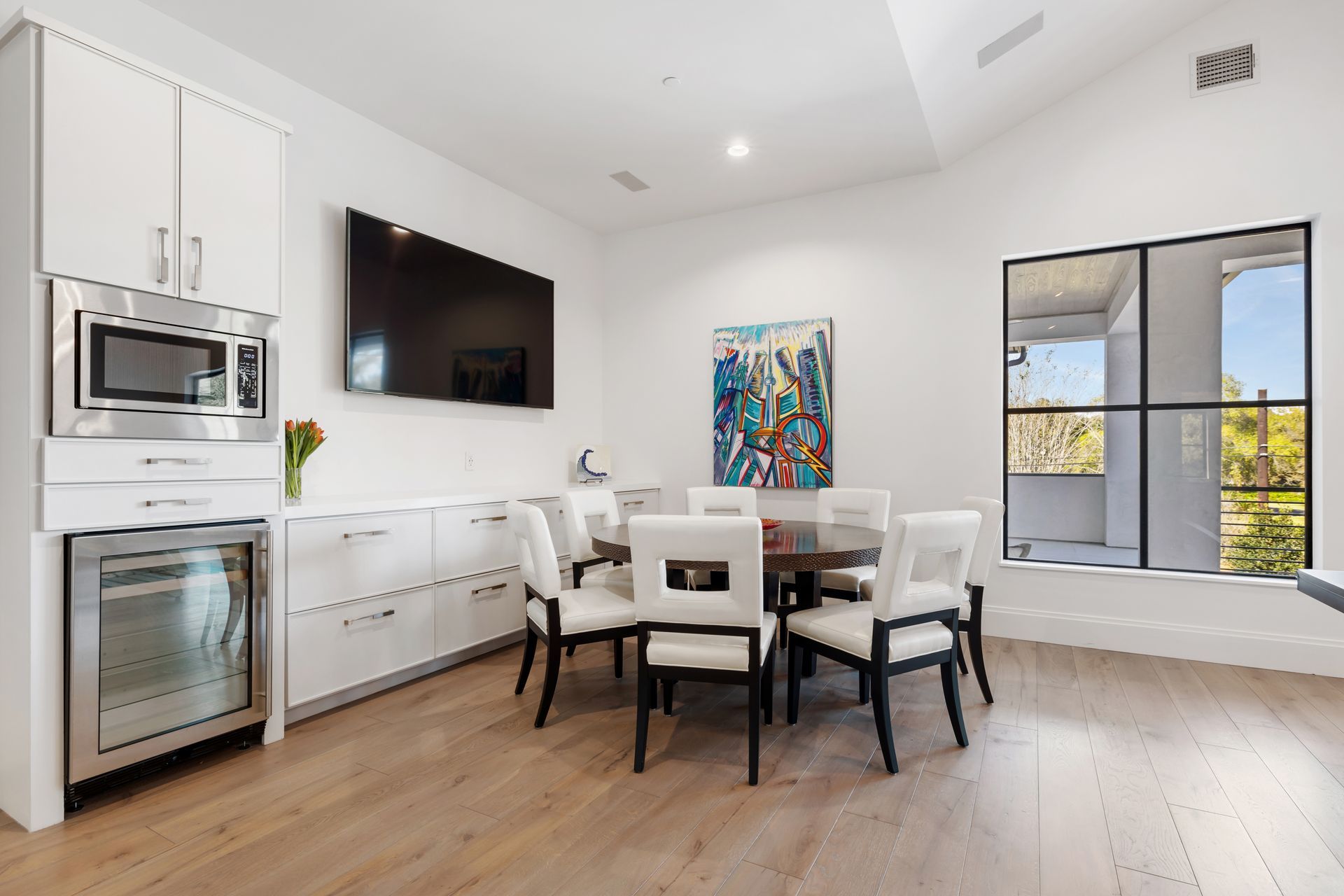 A dining room with a table and chairs and a flat screen tv on the wall.
