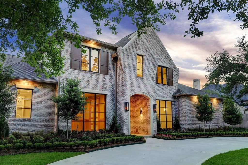 A large brick house with lots of windows and trees in front of it