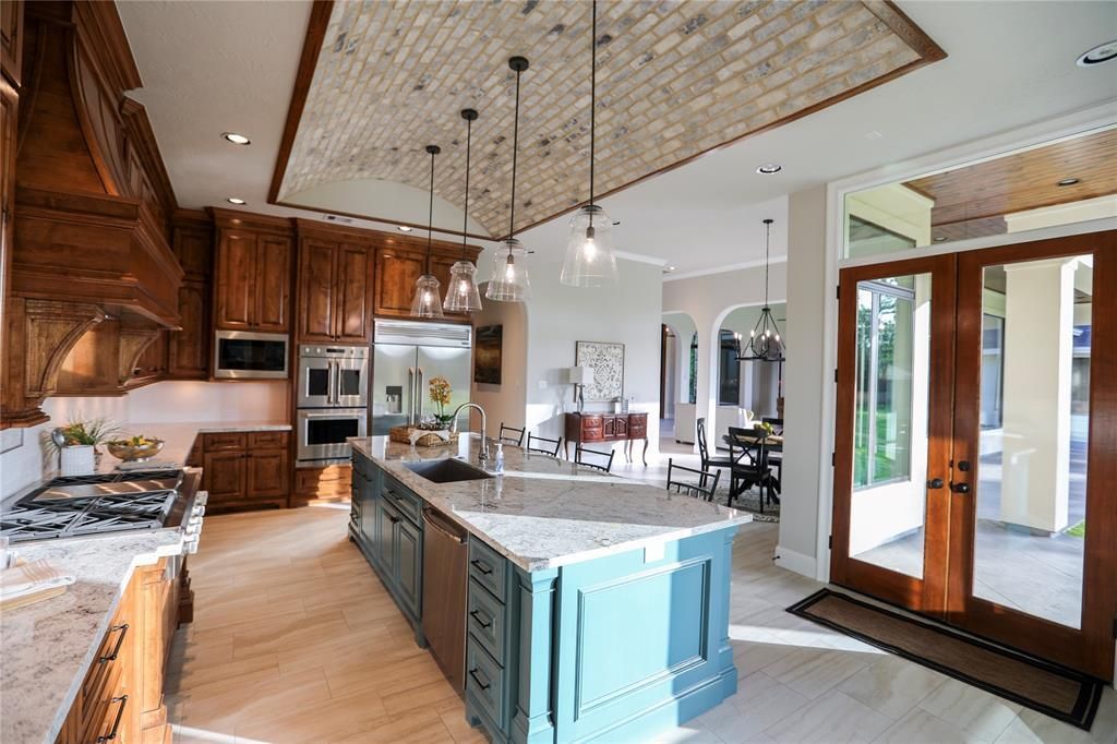 A kitchen with a large island in the middle and a brick ceiling.