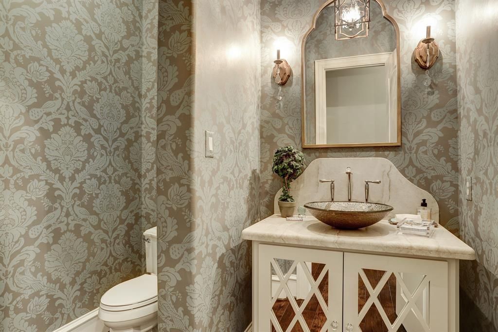 A bathroom with a toilet , sink and mirror.