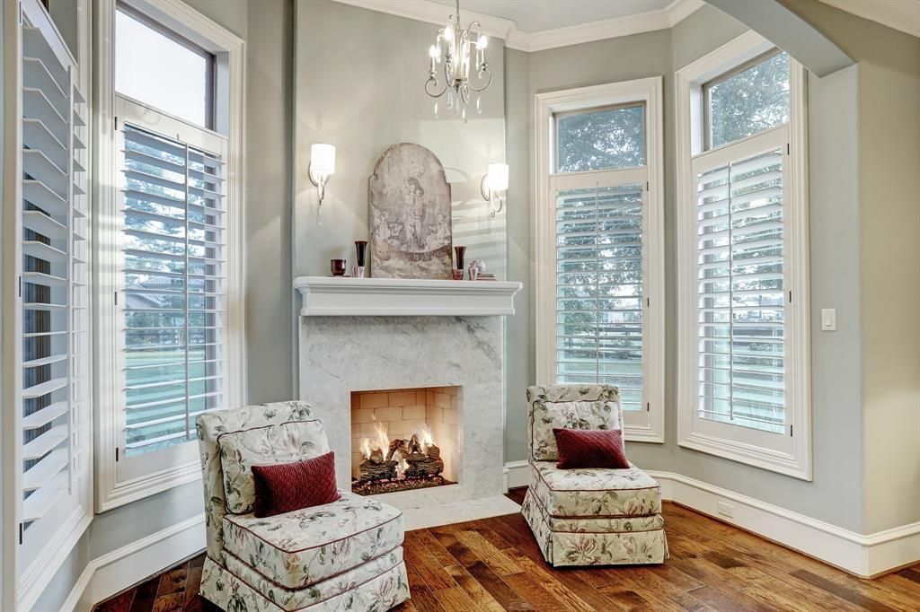 A living room with a fireplace , two chairs , and a chandelier.